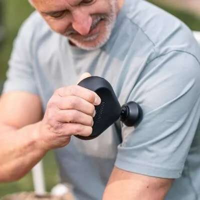 Compact Theragun Mini massage gun shown with its ergonomic body and attachment.