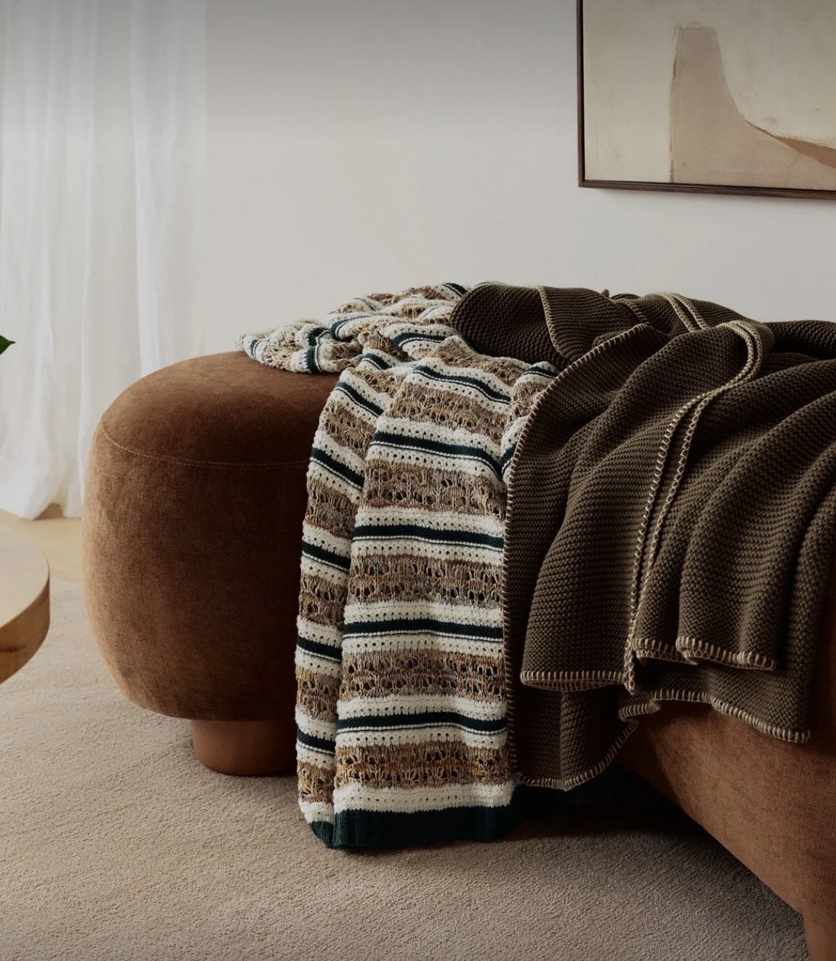 Striped throws layered over a rust-colored sofa for a relaxed, inviting living room. Maison Barbara offers interior design, furnishings and textiles in Zurich and along Lake Zurich.

