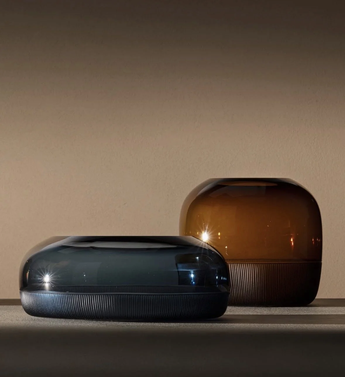 Sculptural glass vessels in deep teal and amber bring color and character to a warm, neutral interior. Discover home accessories and interior styling with Maison Barbara in Zurich and along Lake Zurich.
