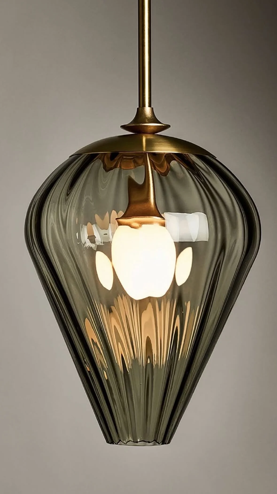 A modern pendant light fixture with a glass shade and a visible light bulb inside.