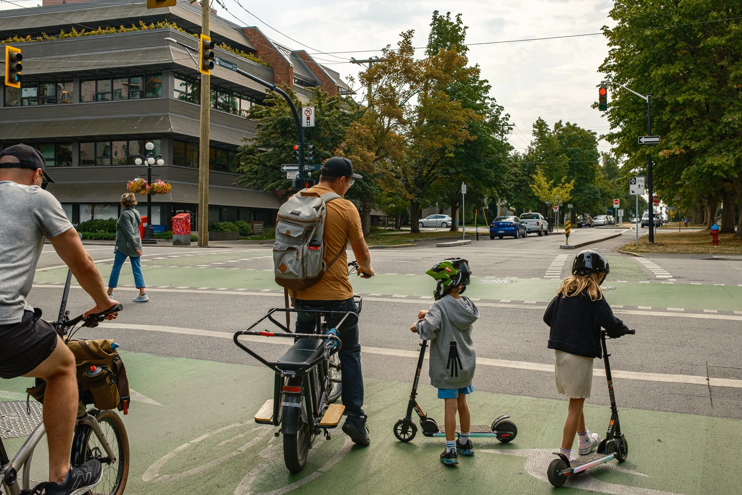 Family on bikes and scooters waiting to cross an intersection