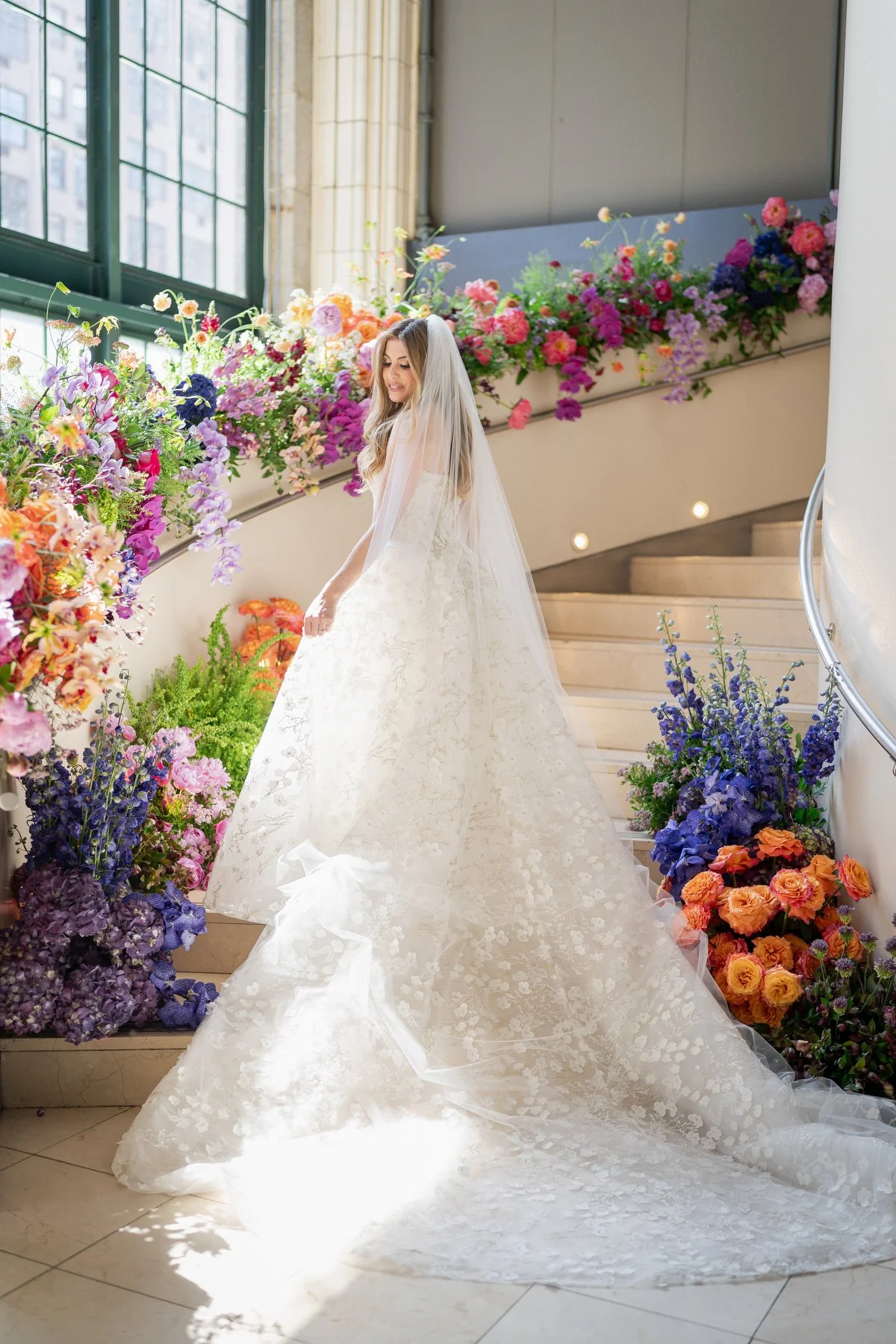 Bride on staircase with colorful floral installation at Guastavinos wedding NYC