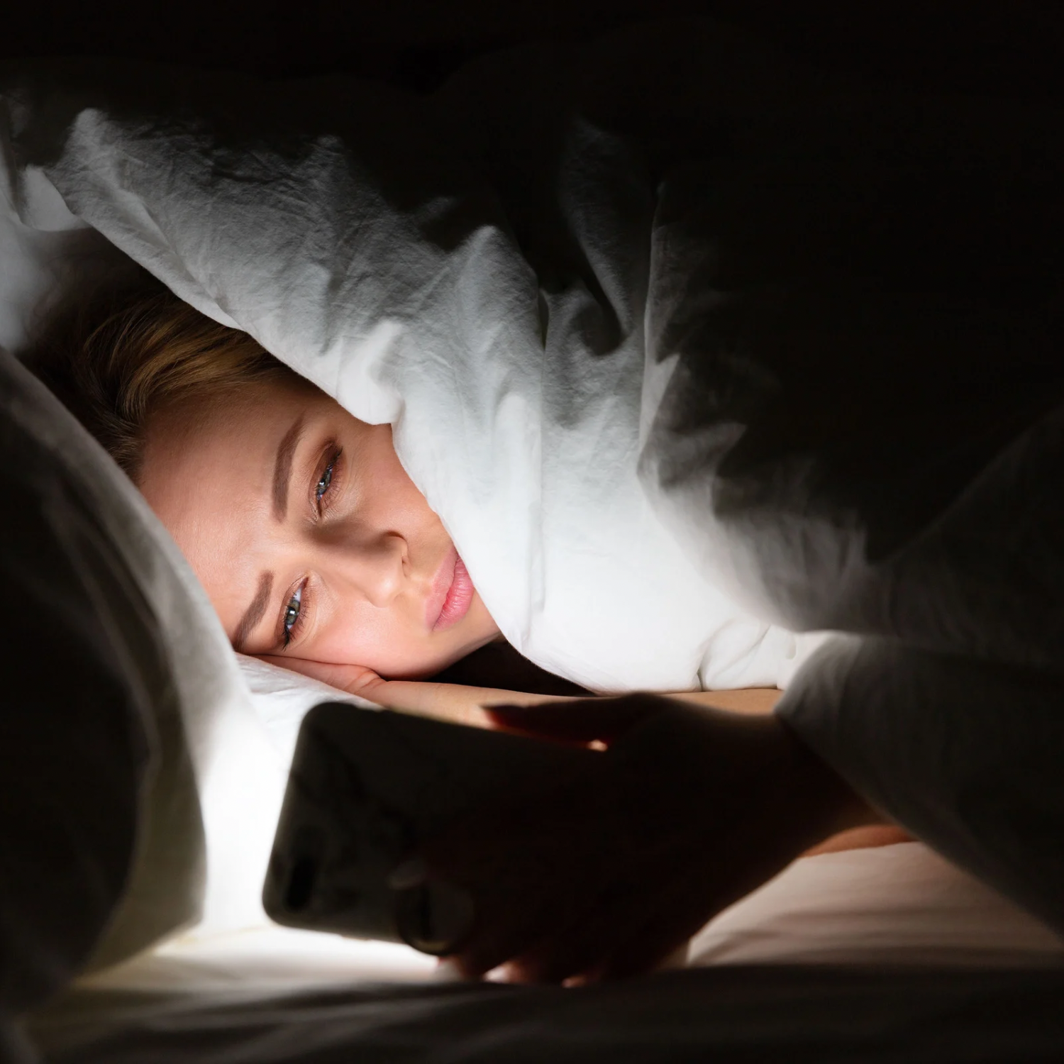 woman using phone in bed