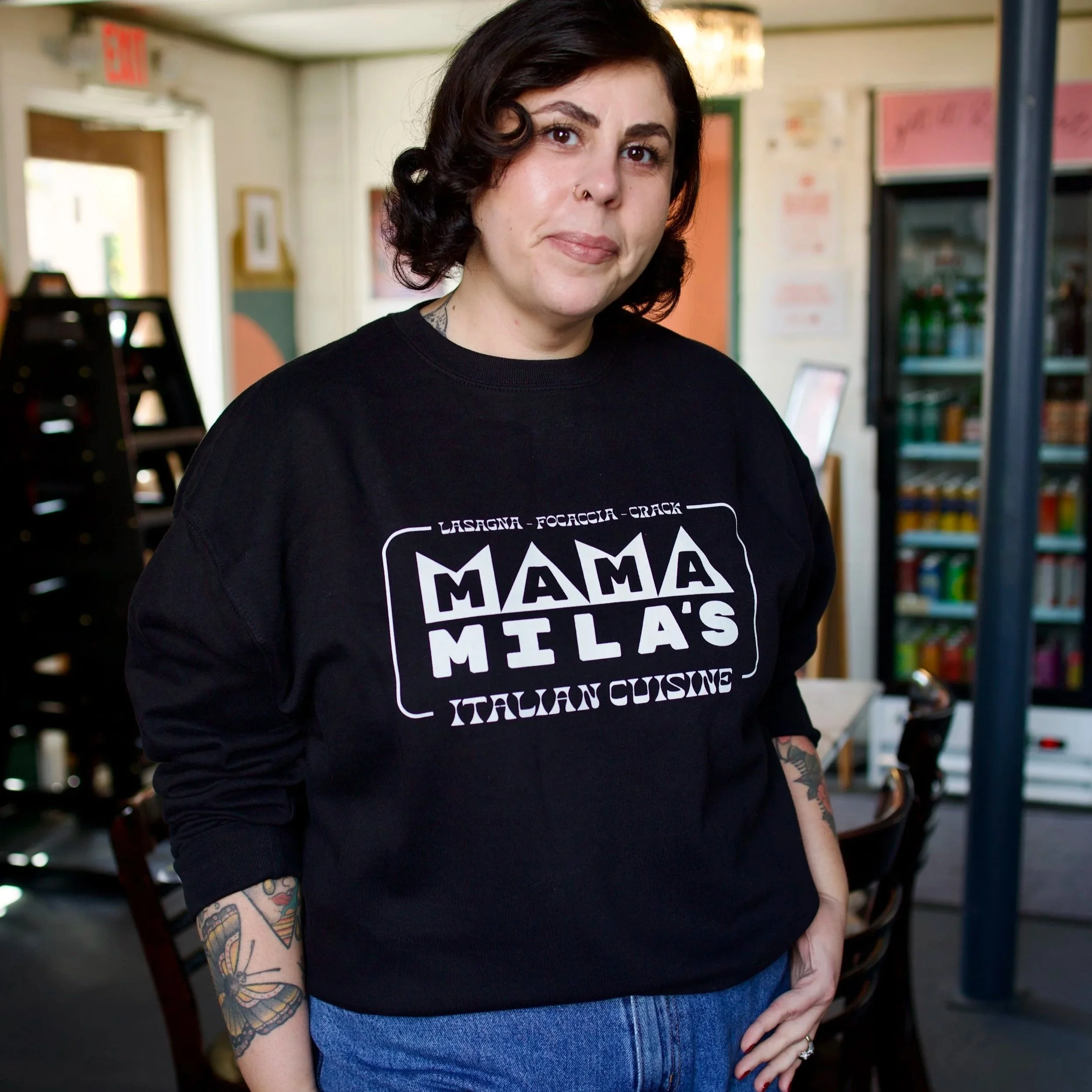 Mila wearing the Black sweatshirt with a white vintage Mama Mila's design on it, featuring the words Focaccia, Lasagna, Crack and Italian Cuisine"