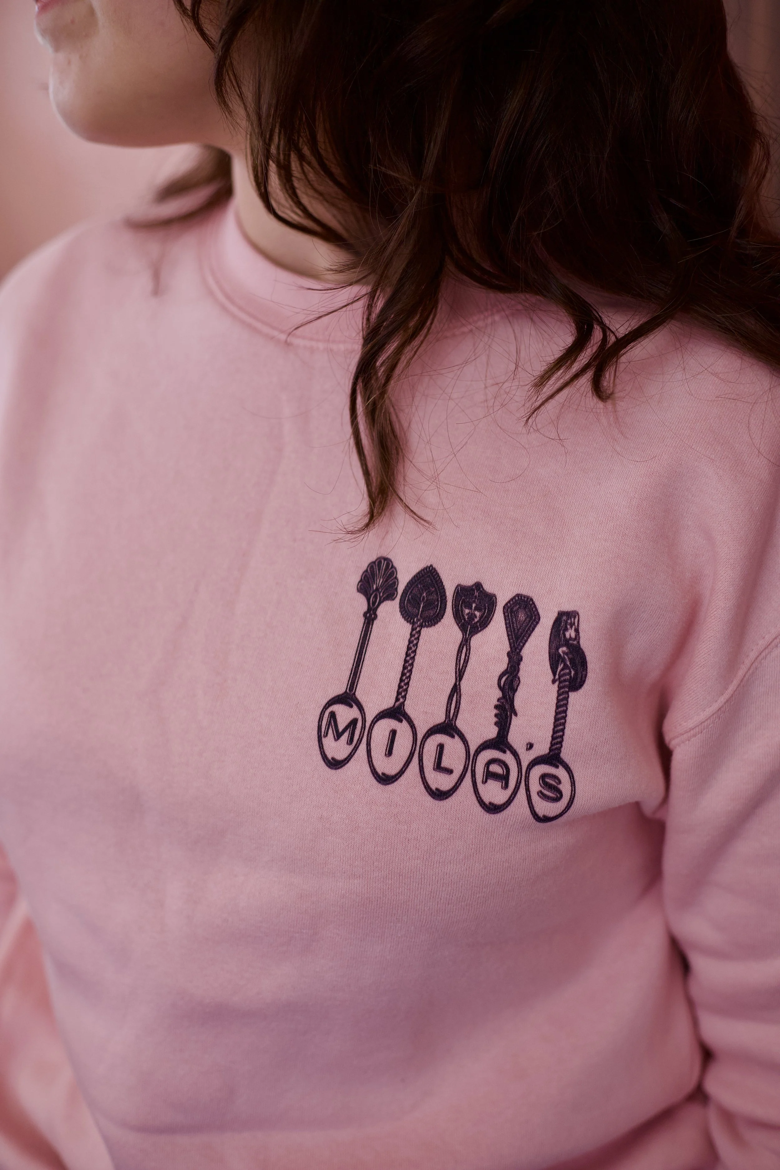 Light pink sweatshirts with vintage spoons spelling out "Mila's"