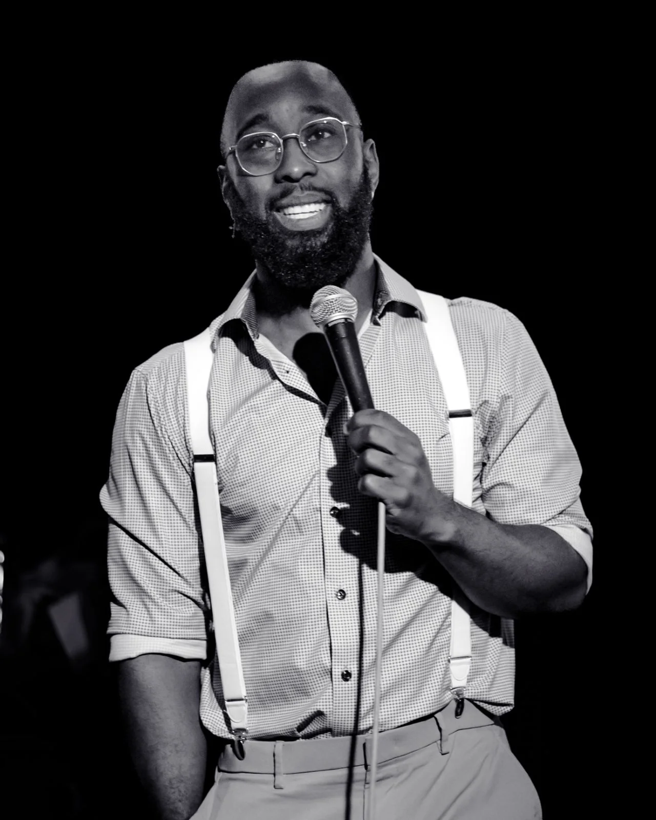 St. James Jackson in suspenders holding a microphone, photographed in black and white.