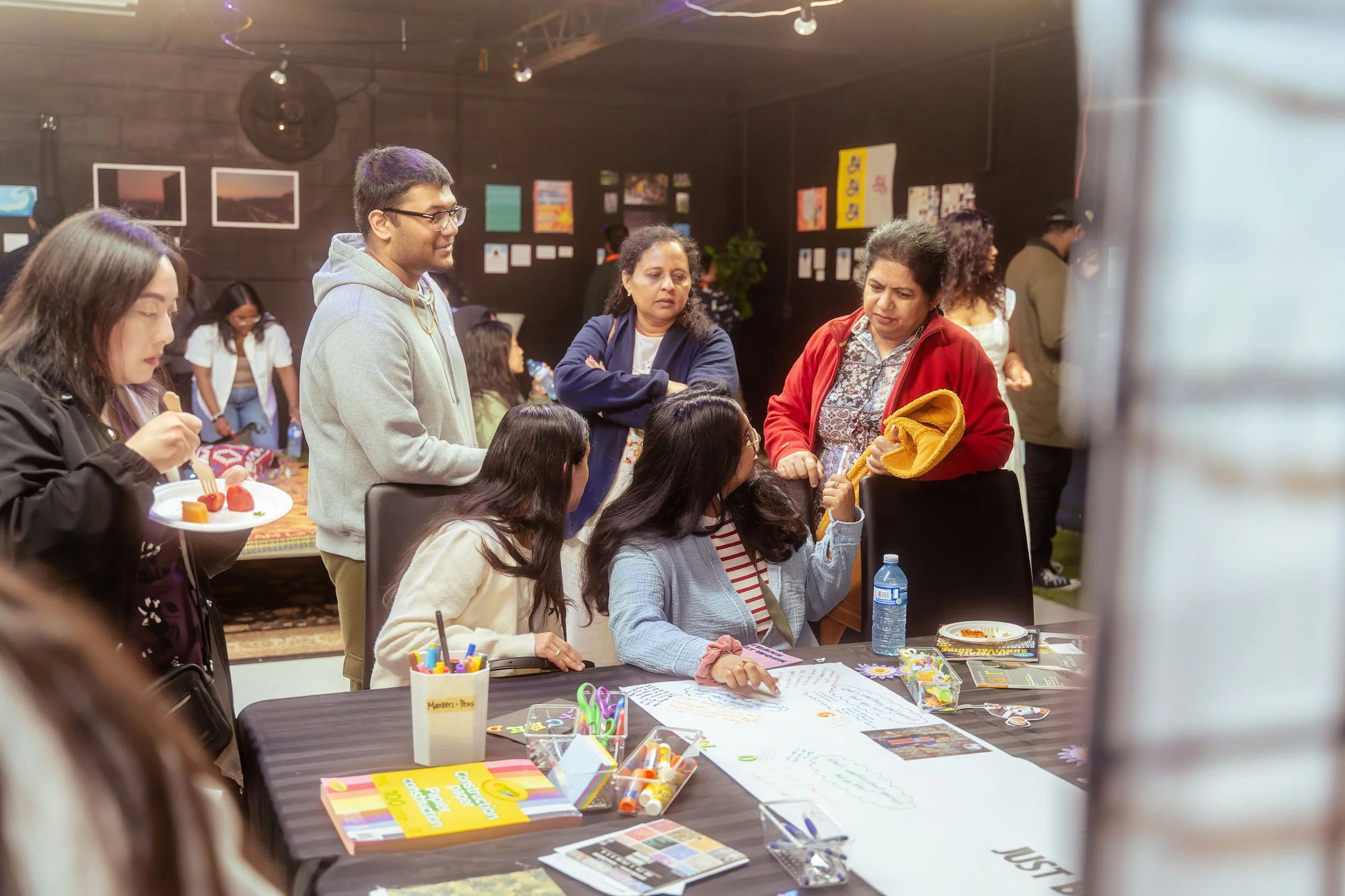 Photos of participants sitting and standing in front of the table conversing with each other.