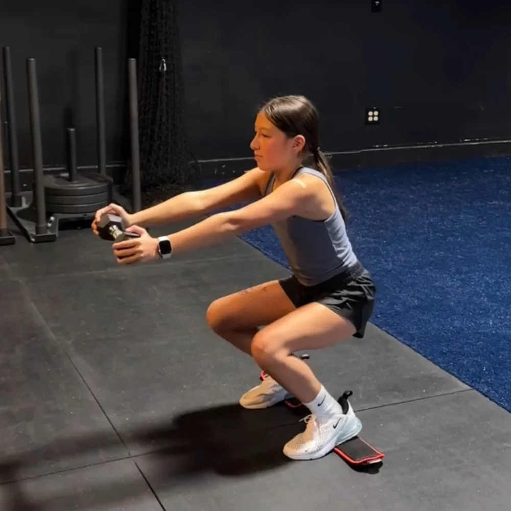 Young athlete holding a goblet squat with a light dumbbell to build leg strength for speed at Char Sports Performance