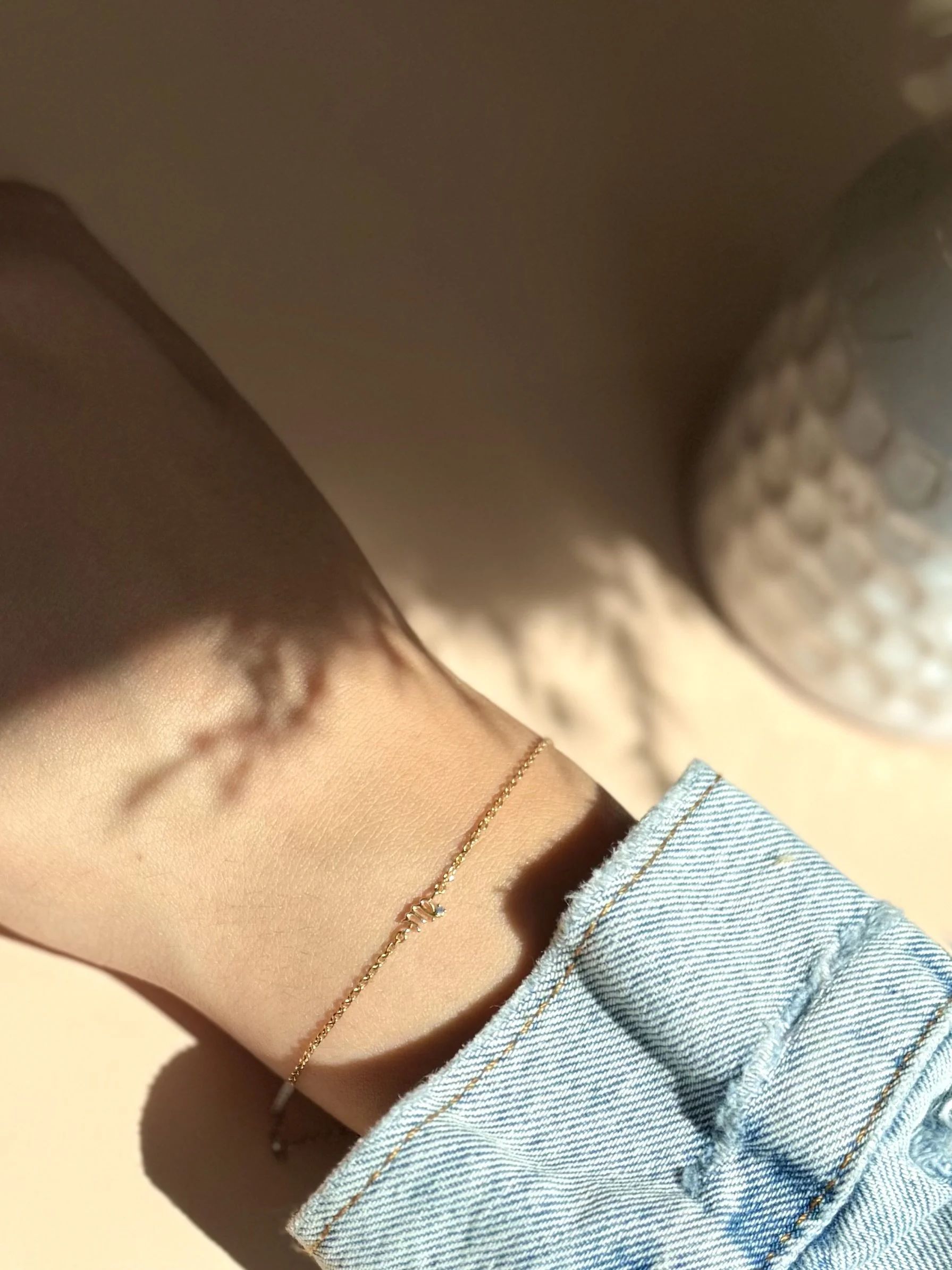 Virgo zodiac bracelet in solid 14k gold shown on model. Natural sapphire birthstone. From The Sparkle Bar in Edmonton. Shop permanent jewelry online