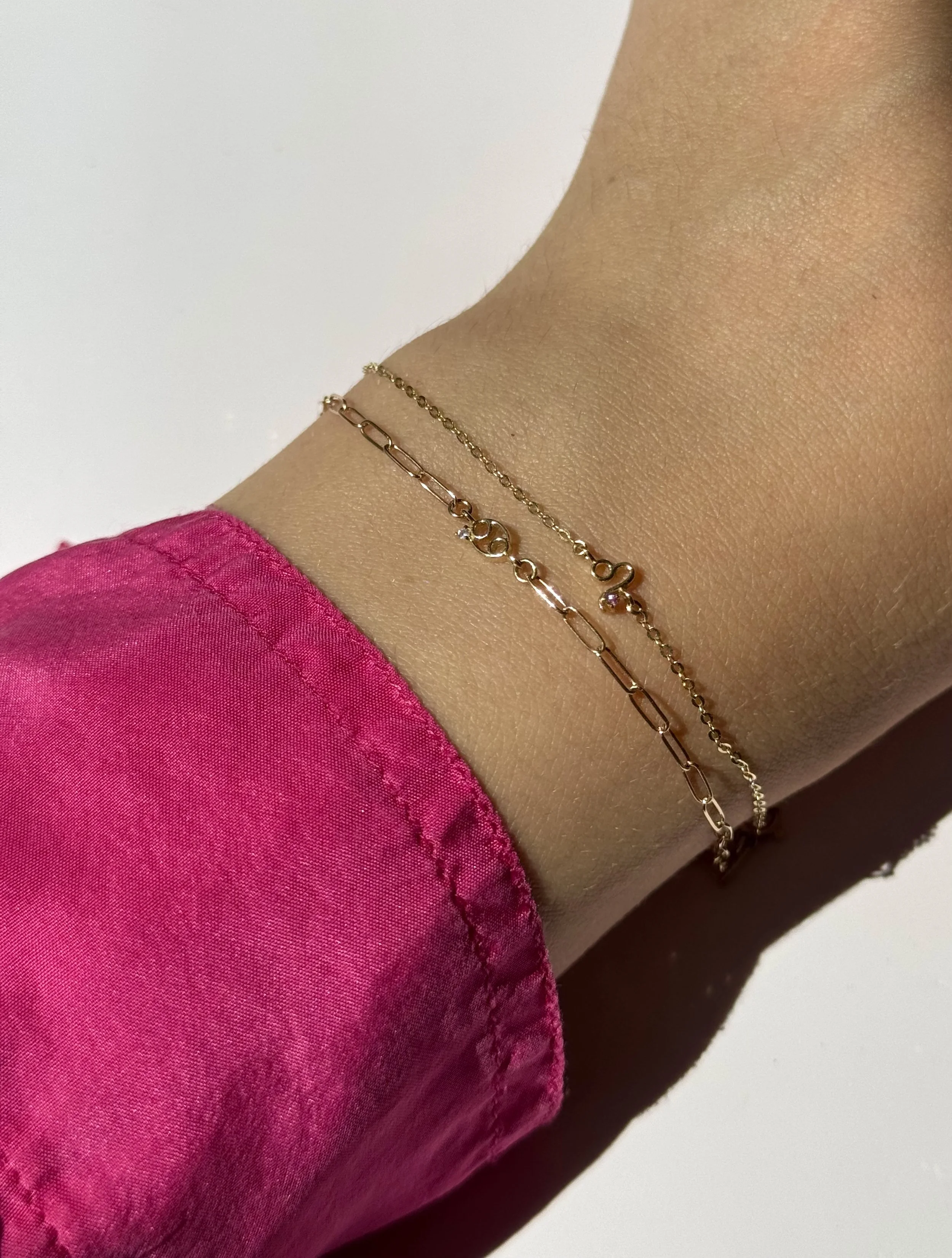 Leo zodiac bracelet in solid 14k gold shown on model. Natural tourmaline birthstone. From The Sparkle Bar in Edmonton. Shop permanent jewelry online