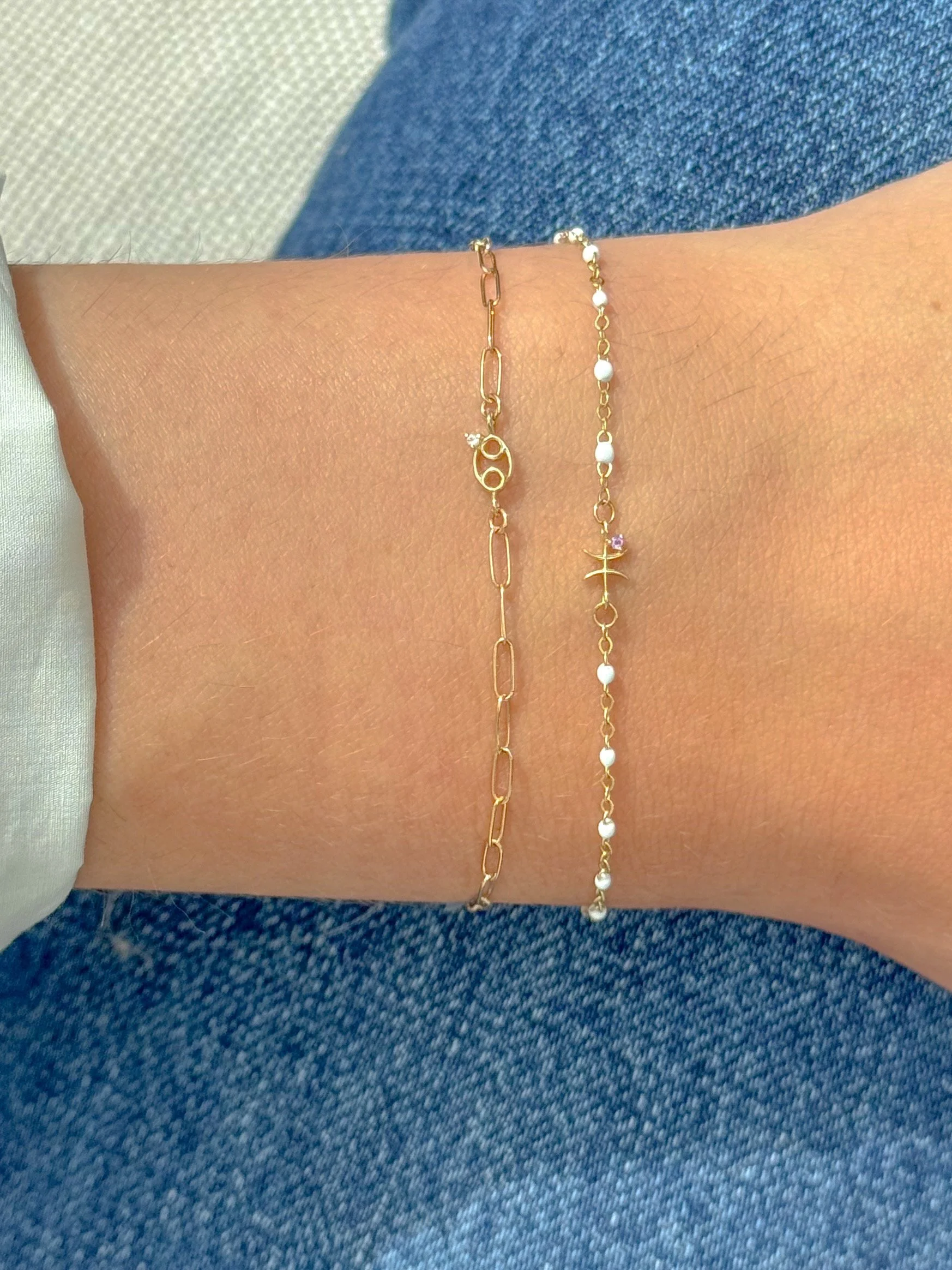 Pisces zodiac bracelet in solid 14k gold shown on model. Natural amethyst birthstone. From The Sparkle Bar in Edmonton. Shop permanent and fine jewelry online
