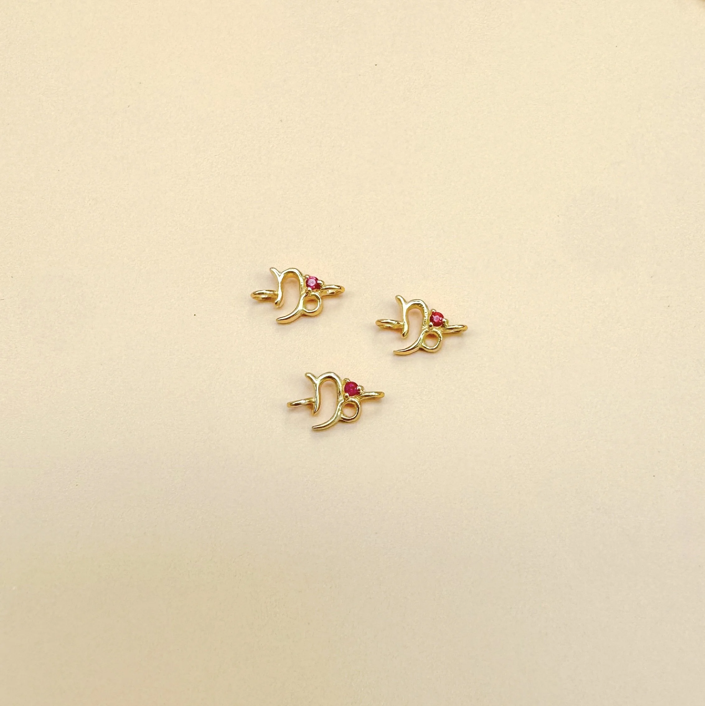 Capricorn zodiac charm in solid 14k gold with natural ruby birthstone. Permanent jewelry by The Sparkle Bar, Edmonton. Shop zodiac connectors online