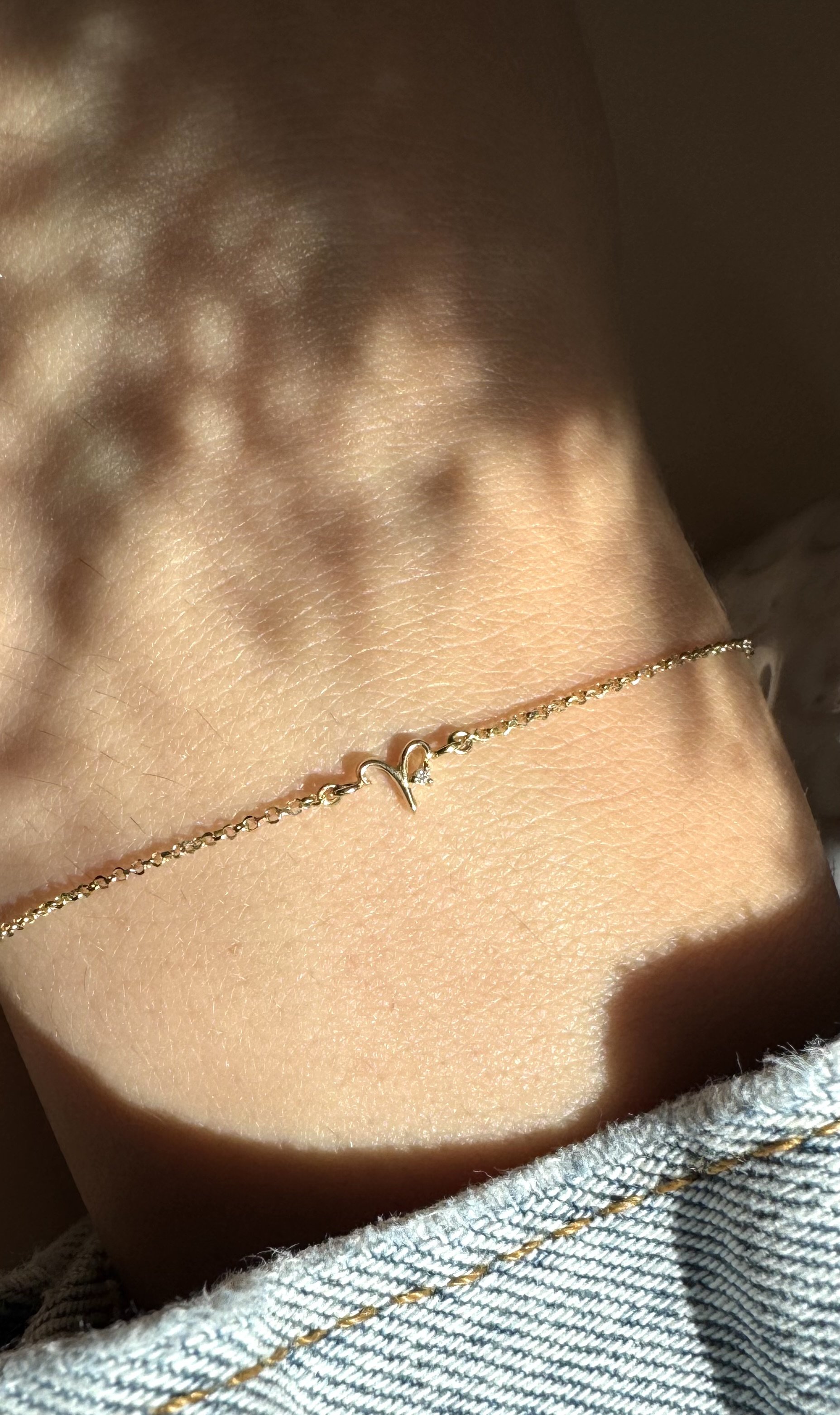 Aries zodiac bracelet in solid 14k gold shown on model. Natural diamond birthstone. From The Sparkle Bar in Edmonton. Shop fine and permanent jewelry online