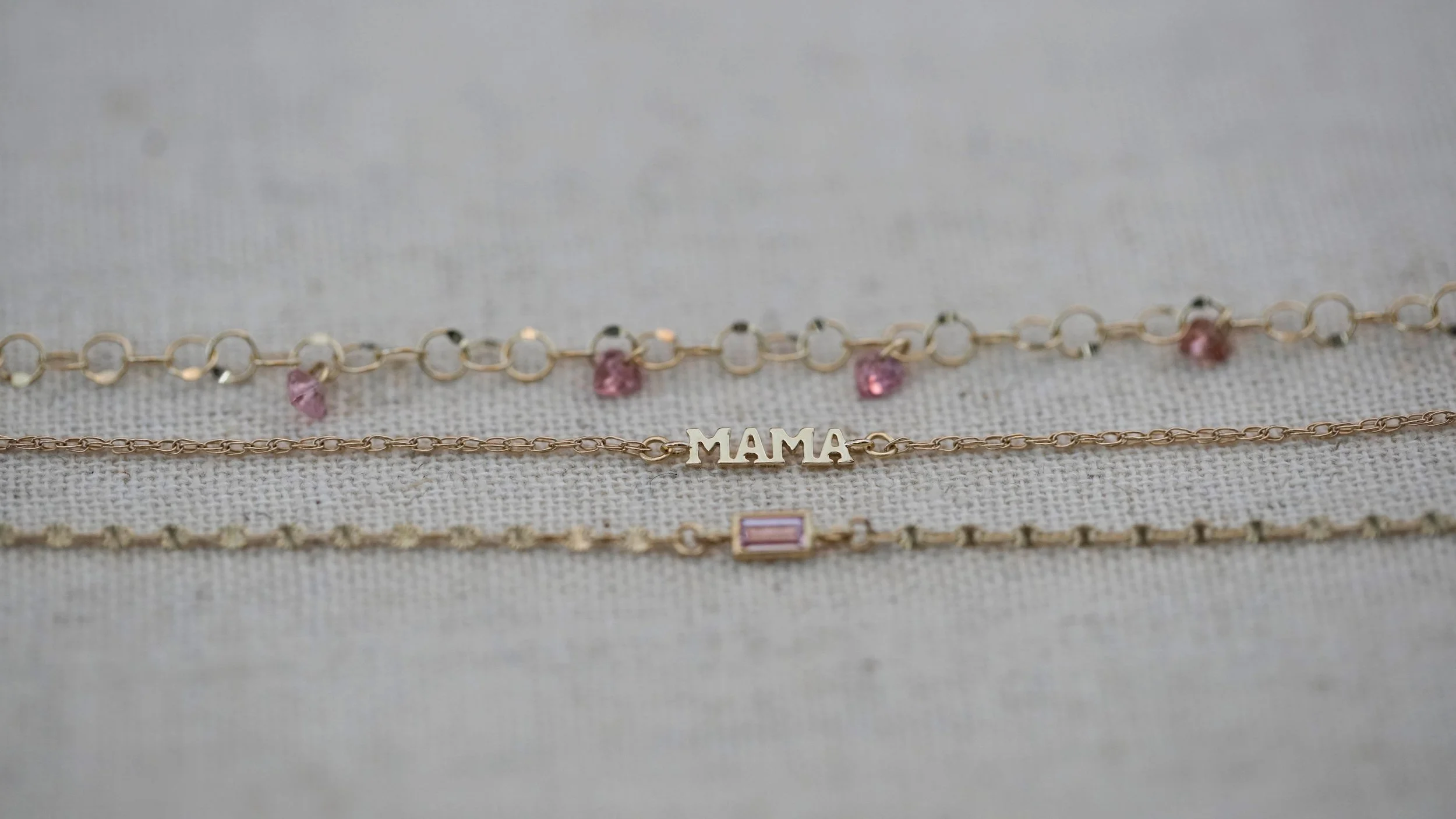 A stack of solid 14k gold bracelets (permanent bracelets or with a clasp) featuring the MAMA connector from The Sparkle Bar in Edmonton