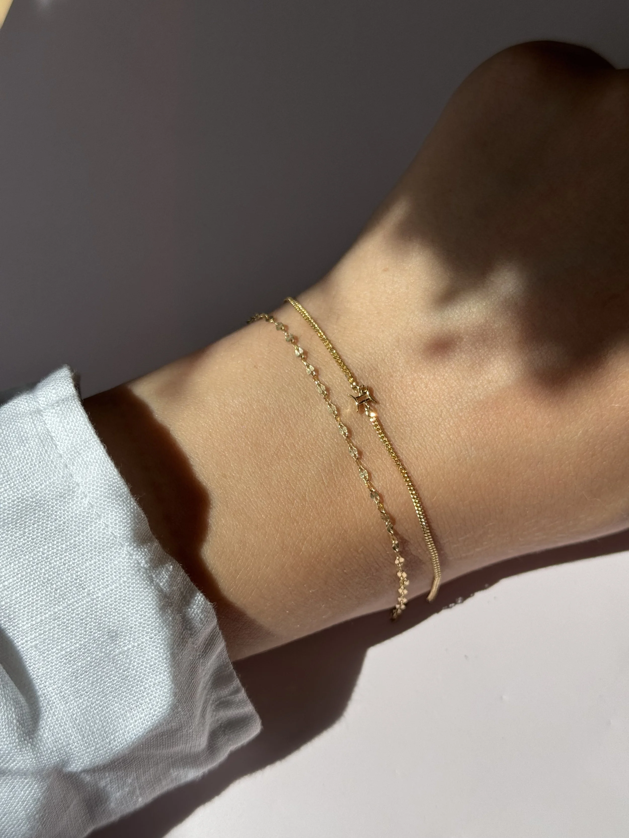 Gemini zodiac bracelet in solid 14k gold shown on model. Natural citrine birthstone. From The Sparkle Bar in Edmonton. Shop permanent jewelry online