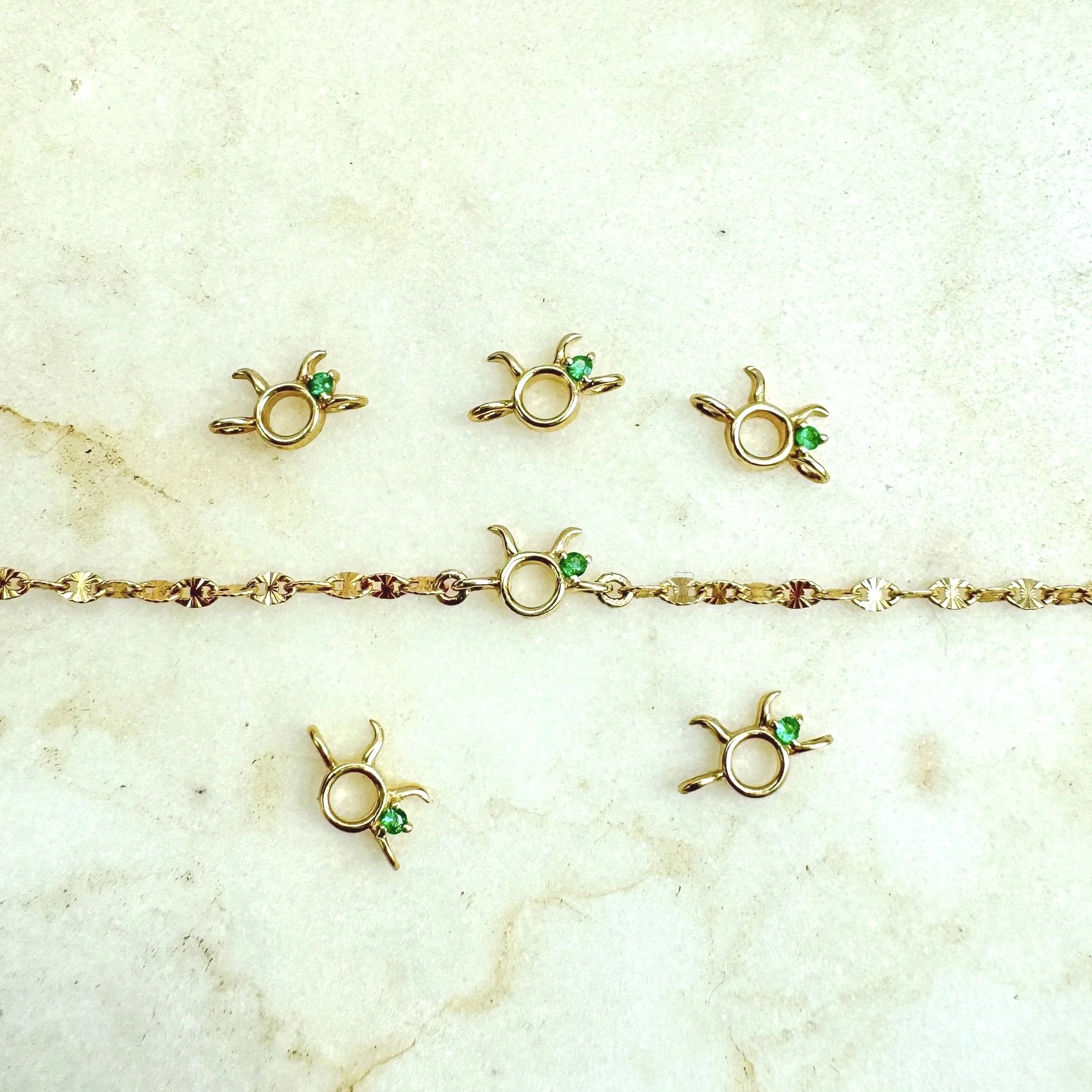 Taurus zodiac charm from The Sparkle Bar. Solid 14k gold with natural emerald birthstone. Shop permanent jewelry online from Edmonton. Limited availability