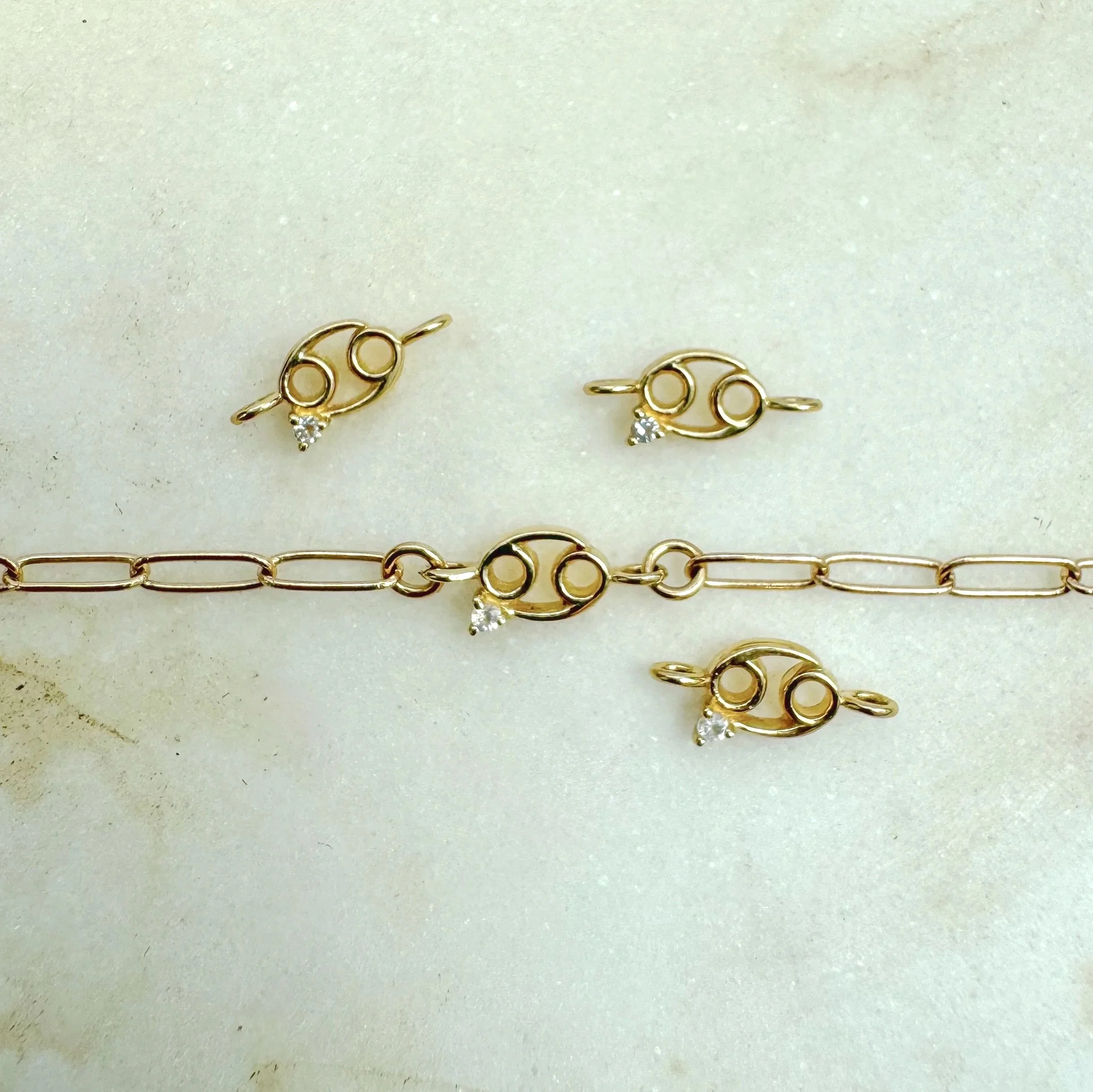 Cancer zodiac charm from The Sparkle Bar. Solid 14k gold with natural moonstone birthstone. Shop permanent jewelry online from Edmonton.