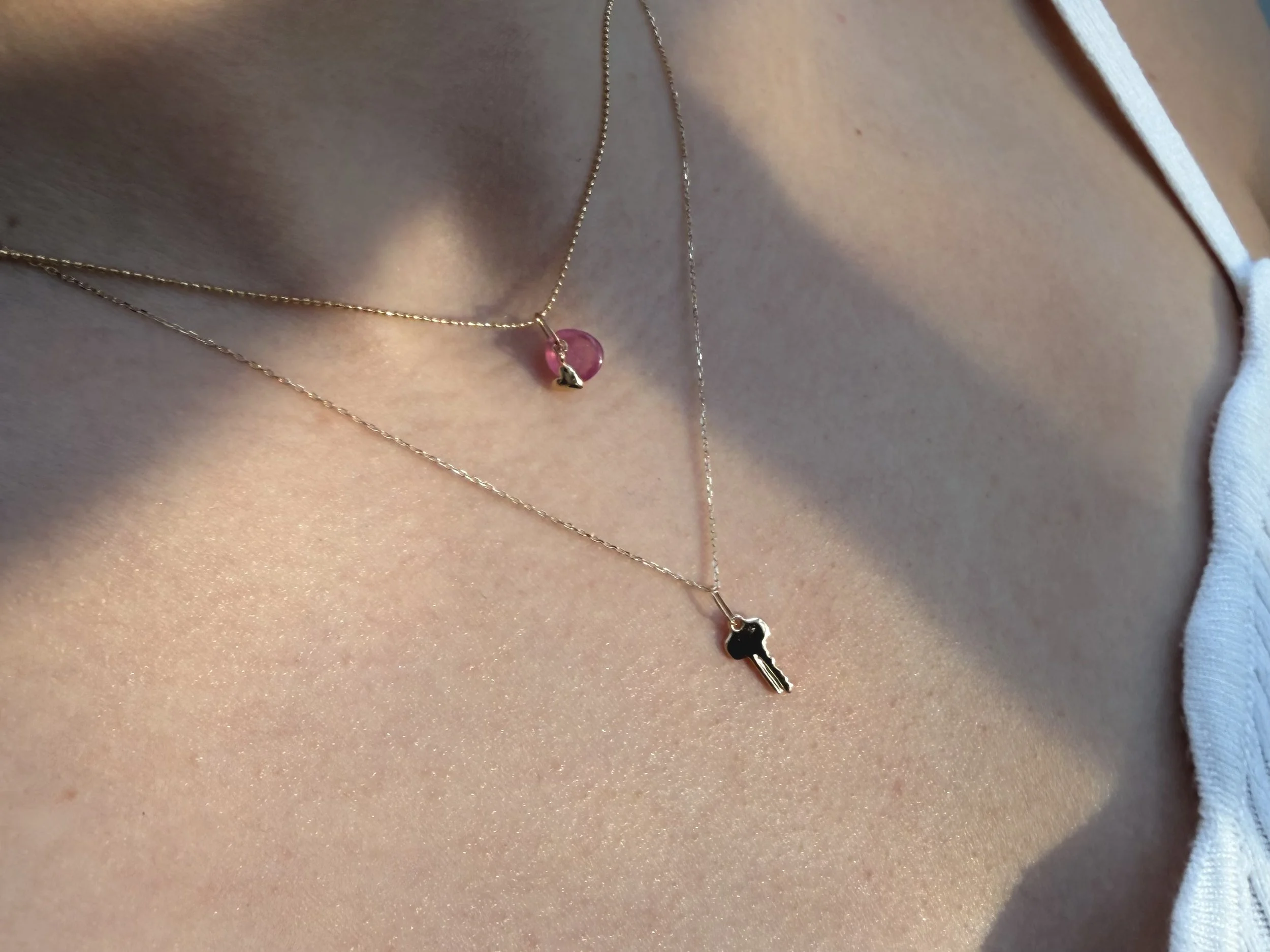 14k gold key charm necklace layered with pink gemstone charm on fine chain, worn on skin in natural light, delicate everyday jewelry by The Sparkle Bar Edmonton
