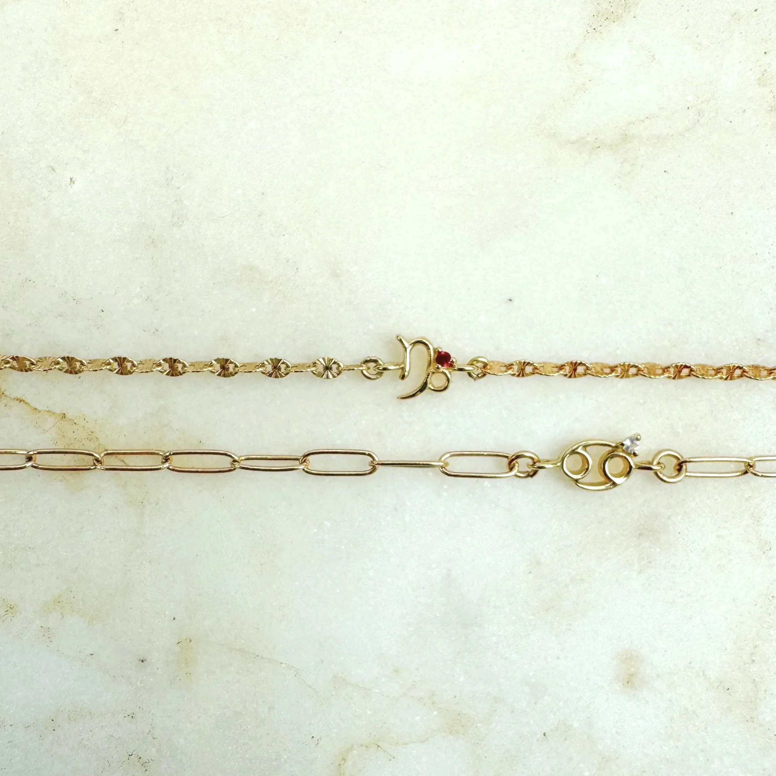 Capricorn zodiac charm from The Sparkle Bar. Solid 14k gold with natural ruby birthstone. Shop permanent jewelry online from Edmonton. Limited availability