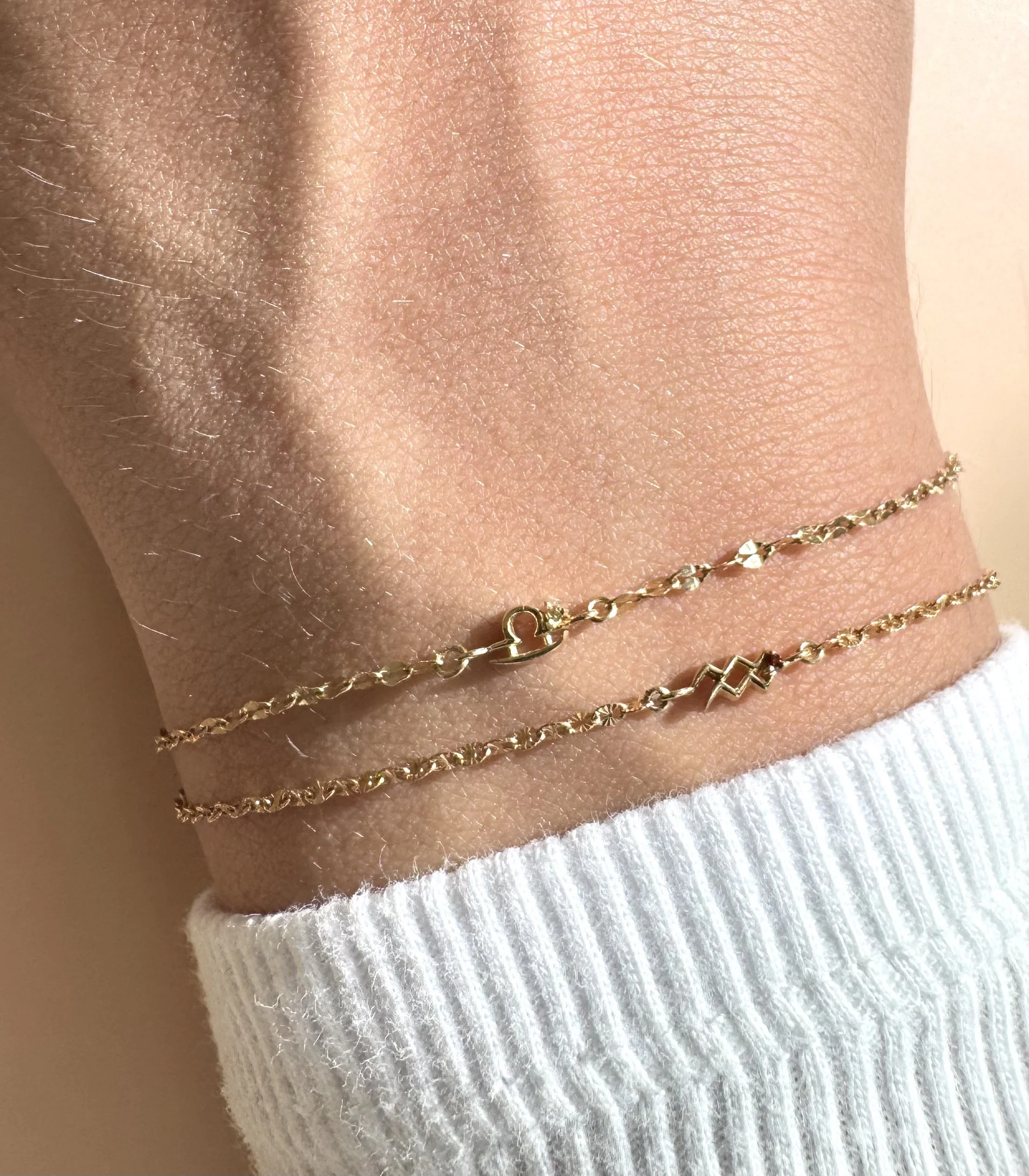 Aquarius zodiac bracelet in solid 14k gold shown on model. Natural garnet birthstone. From The Sparkle Bar in Edmonton. Shop fine and permanent jewelry online