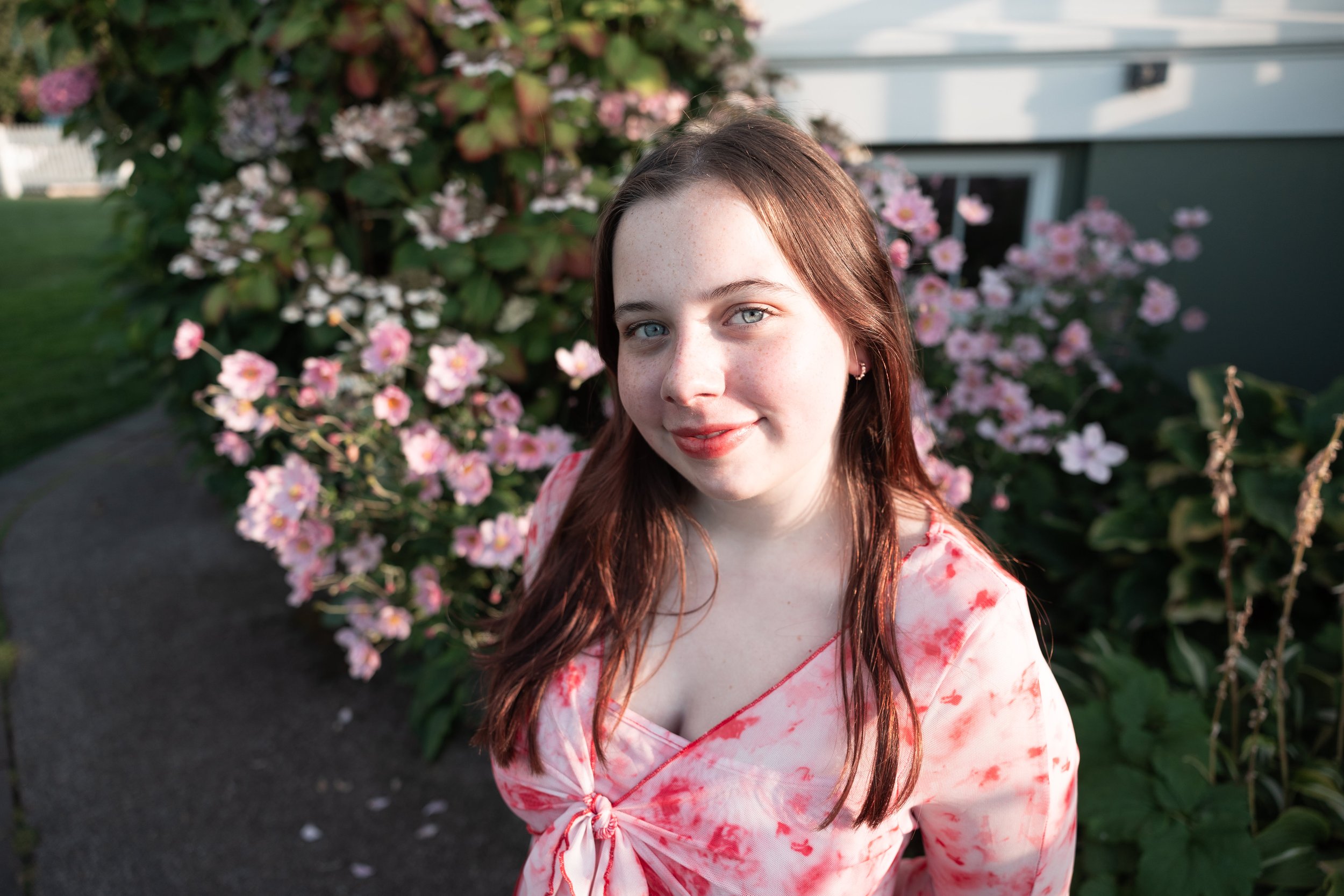 Edmonds High School Senior smiling at Mukilteo lighthouse with pink flowers in the background