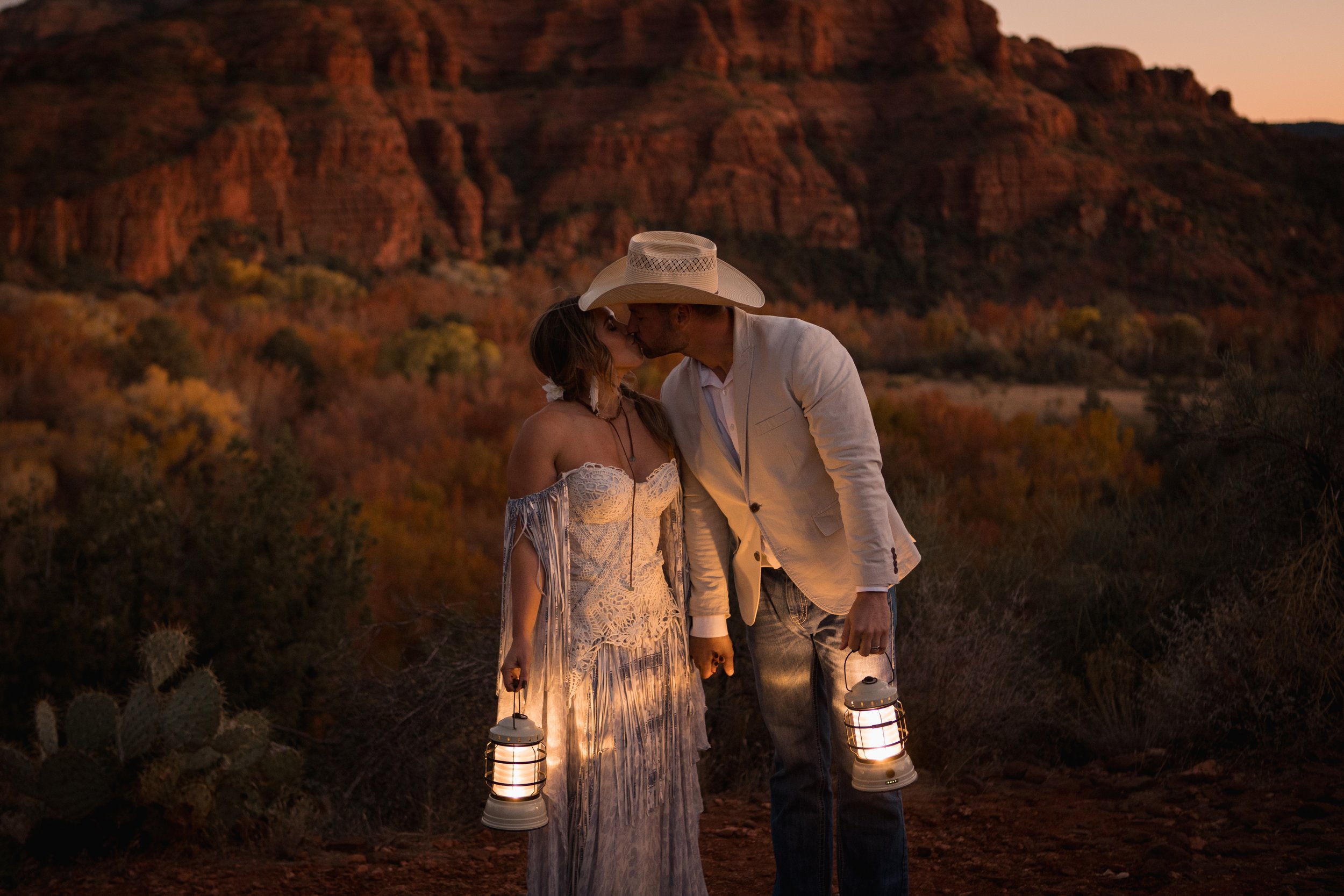 Mesa elopement couple kissing while holding hands and lanterns with a beautiful sorbet sunset