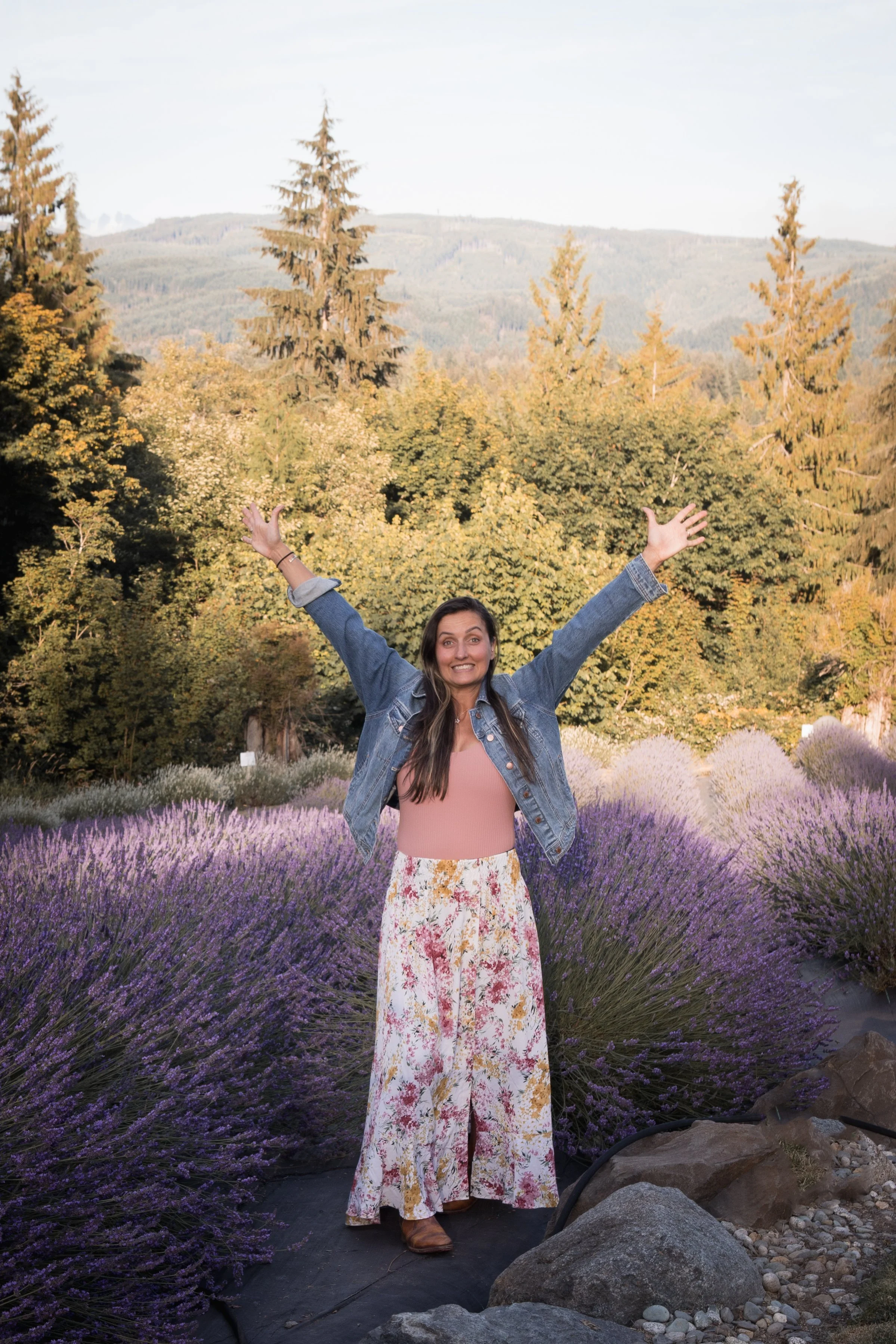 Washington micro wedding photographer in a lavender field, celebrating with hands up and big smile the woods of the North Cascades with camera