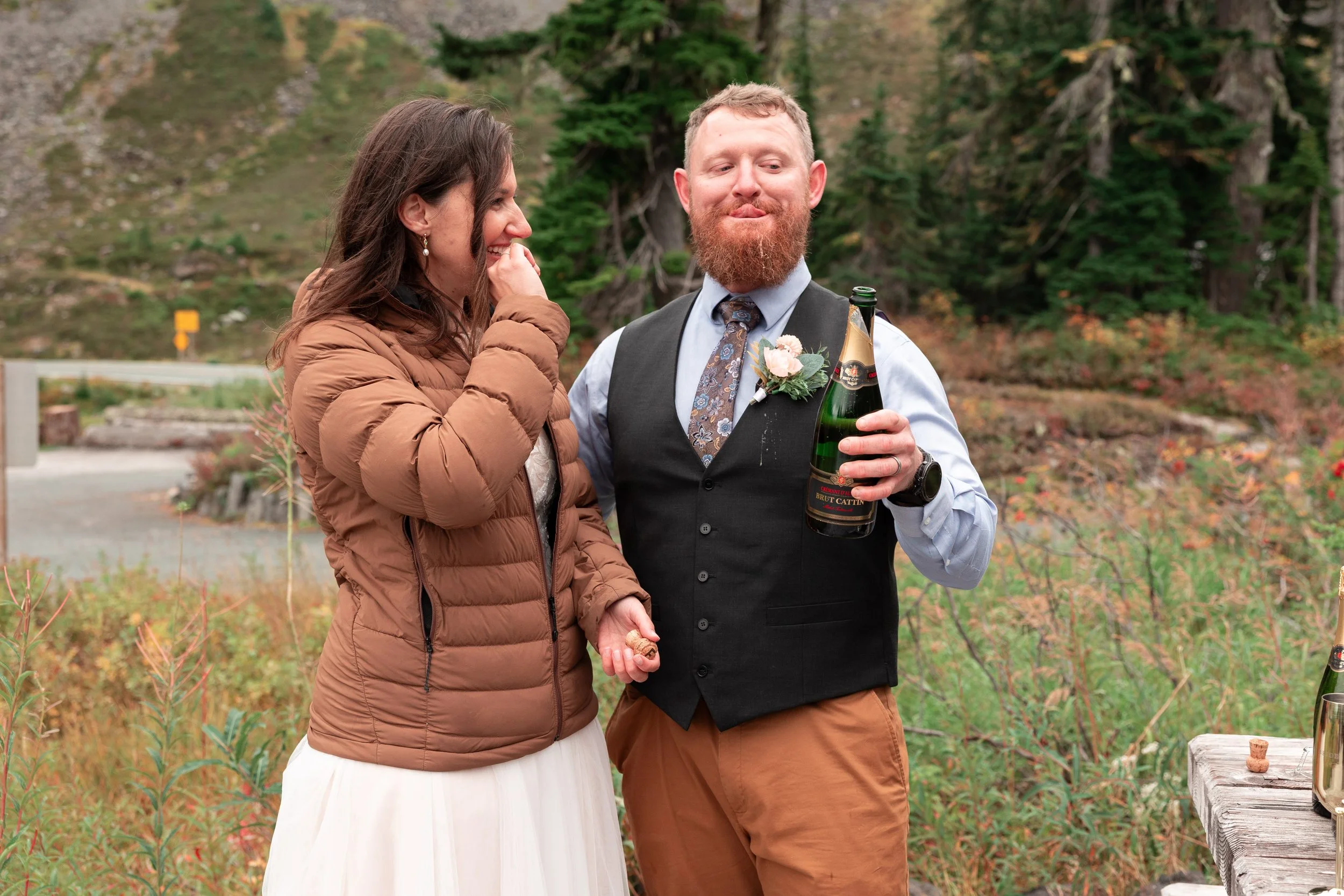Champagne toast with the bride laughing at the groom in the Mt. Baker National Forest of the Cascade Mountains