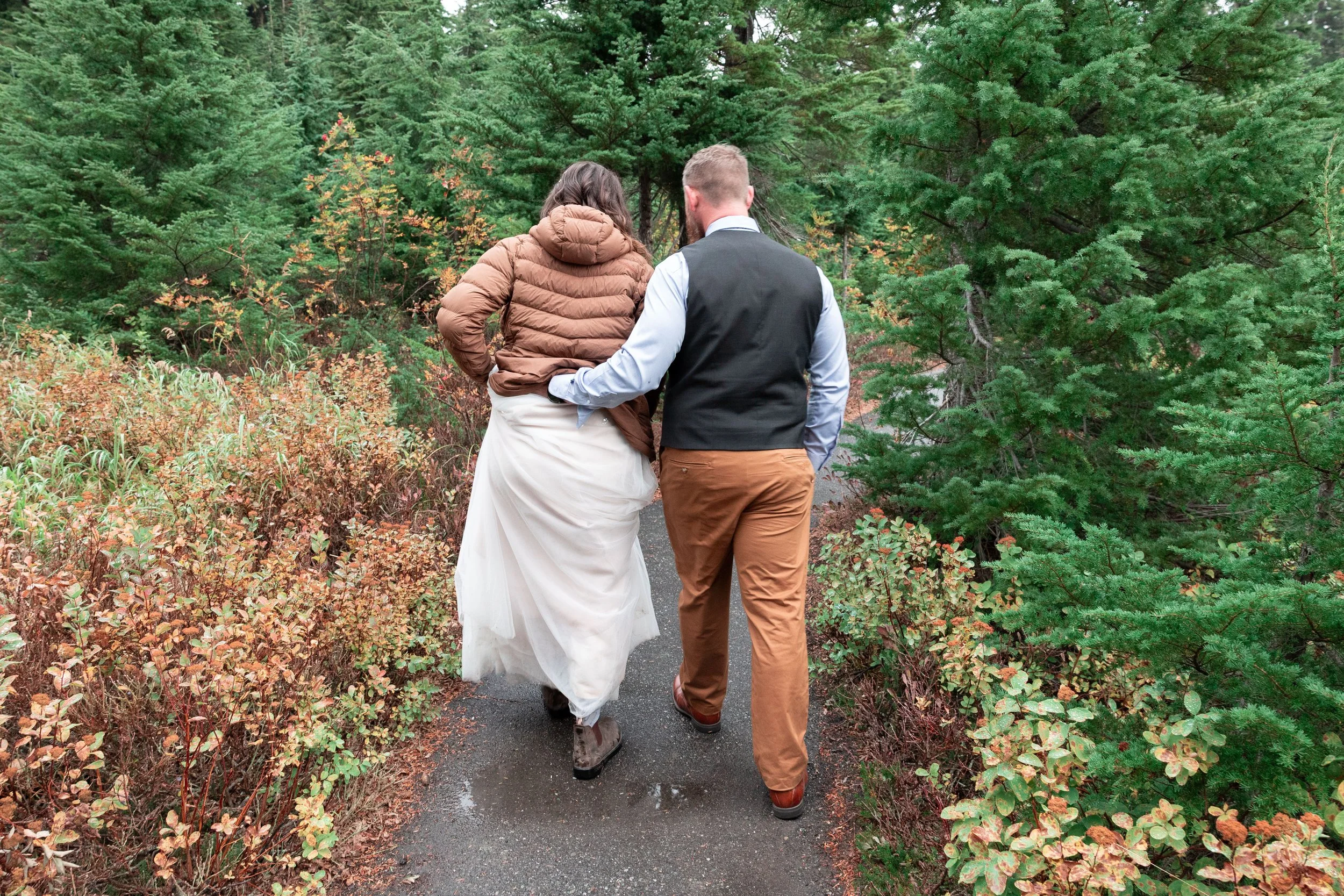Mt. Baker Washington bride and groom walking in the wood,  groom holding her dress up