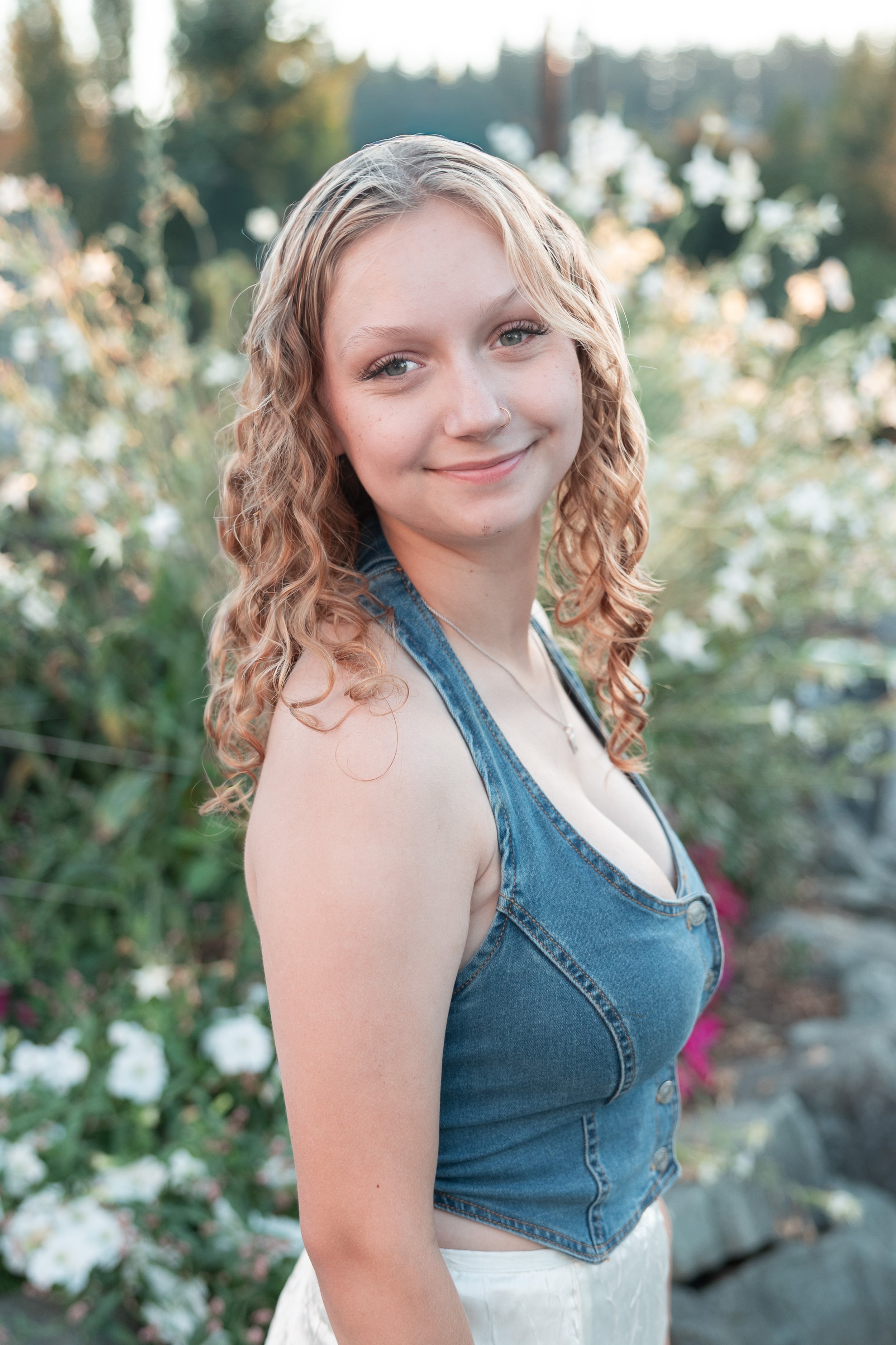 Snohomish Glacier High school senior girl photo session in the flowers at golden hour wearing denim top and white skirt smiling at the camera