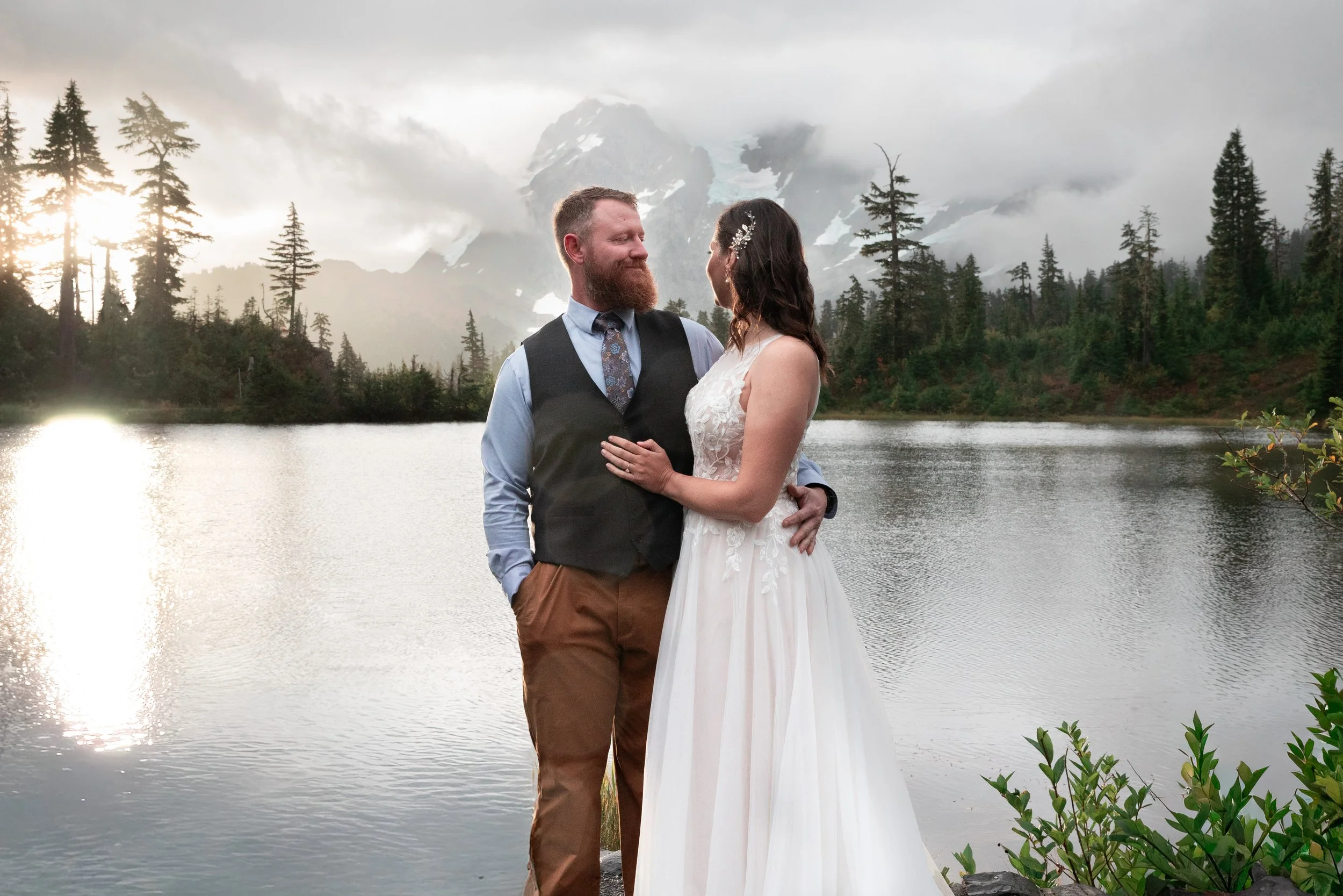 Washington wedding photographer, Groom holding bride and looking into her eyes as she looks at the sunrise, Picture Lake Mt. Baker micro-wedding