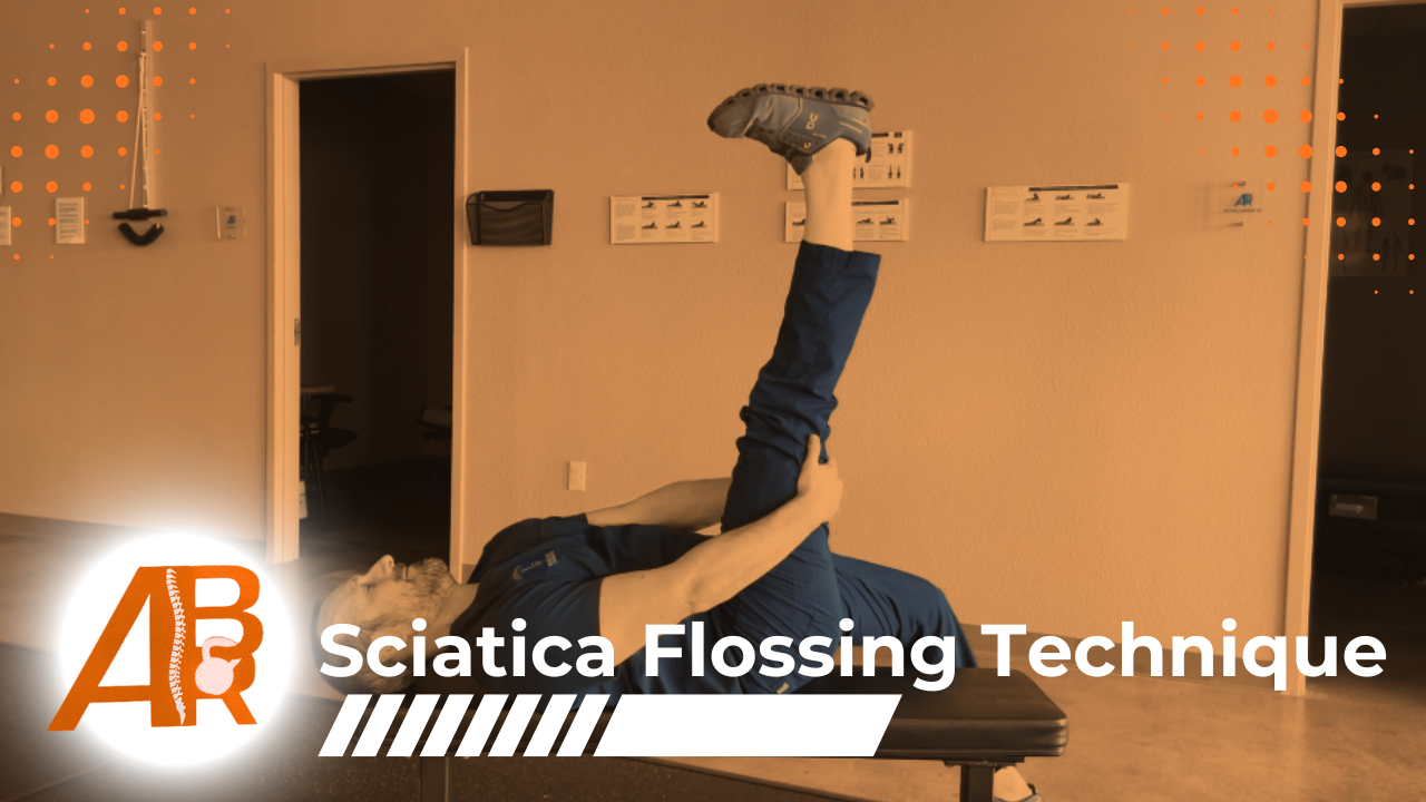 A man lying on an examination table performing a stretching exercise, holding one leg straight up while keeping the other leg on the table, demonstrating a sciatica flossing technique.