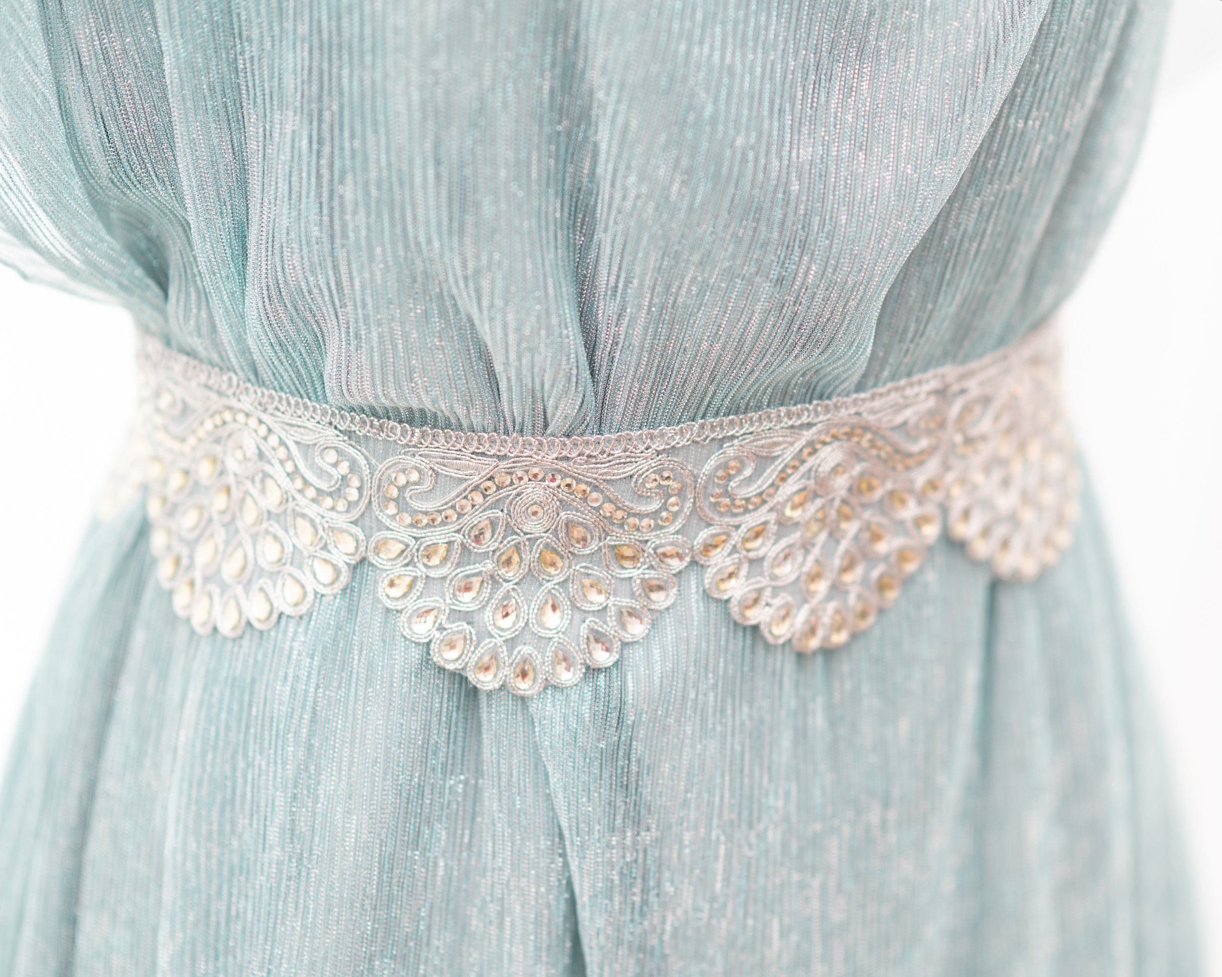 close up of the wide silver belt in the shape of semi circles with waterdrop shaped clear rhinestones.