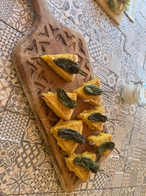 Spanish tortilla wedges with green peppers on a wooden board