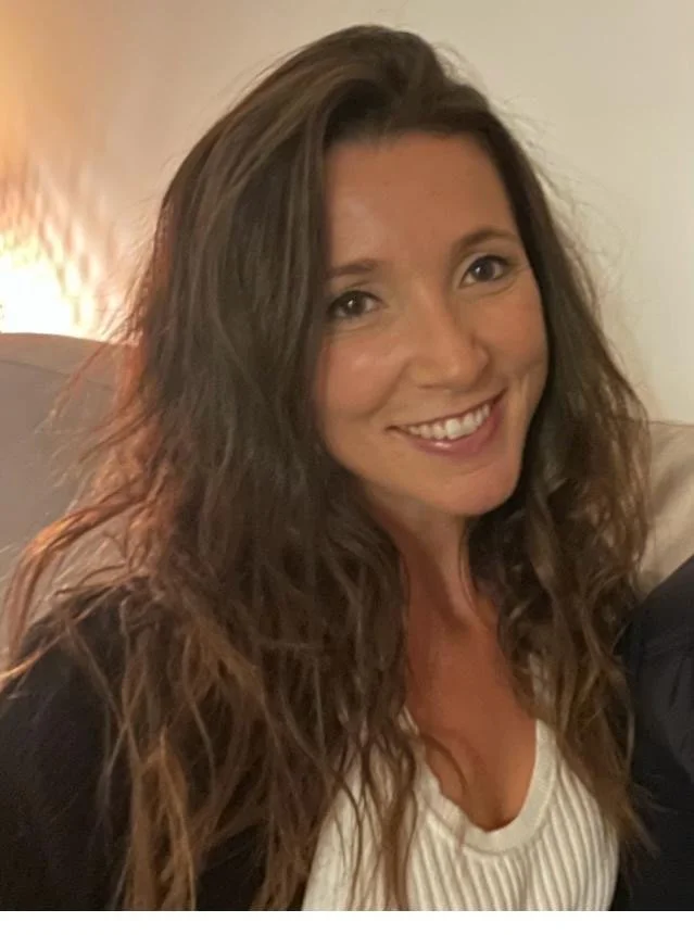 Hannah our yoga teacher smiling woman with long brown hair wearing a white top