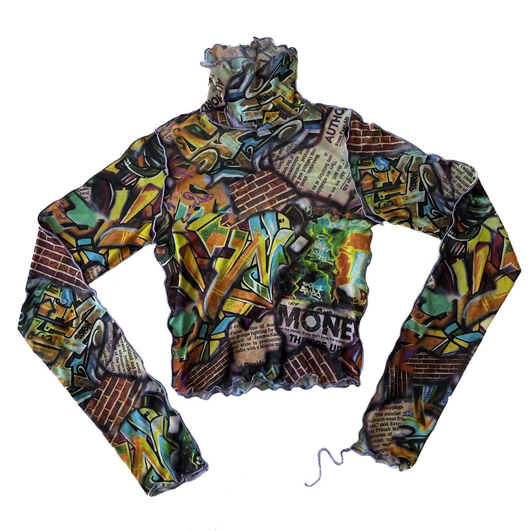 A long-sleeved shirt with a graffiti-style design featuring bright colors, brick patterns, newspaper print, and various abstract shapes.