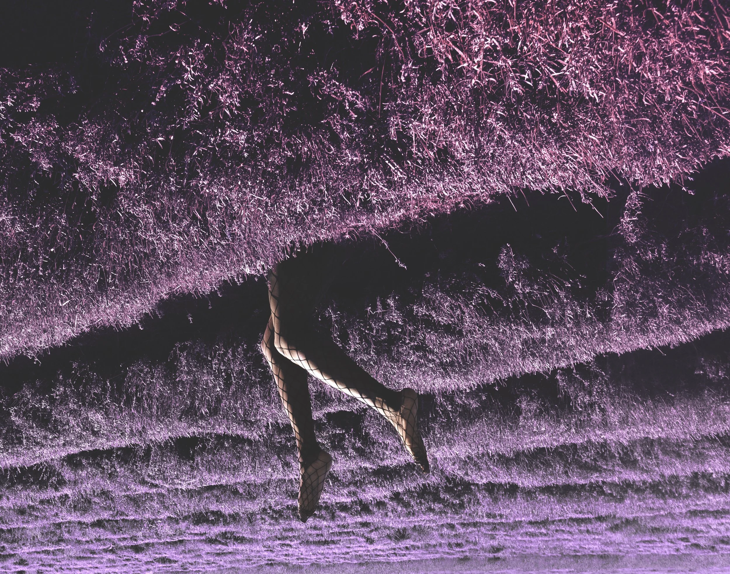 Person in fishnet stockings and high heels standing on a seashore with purple-lit waves crashing behind.