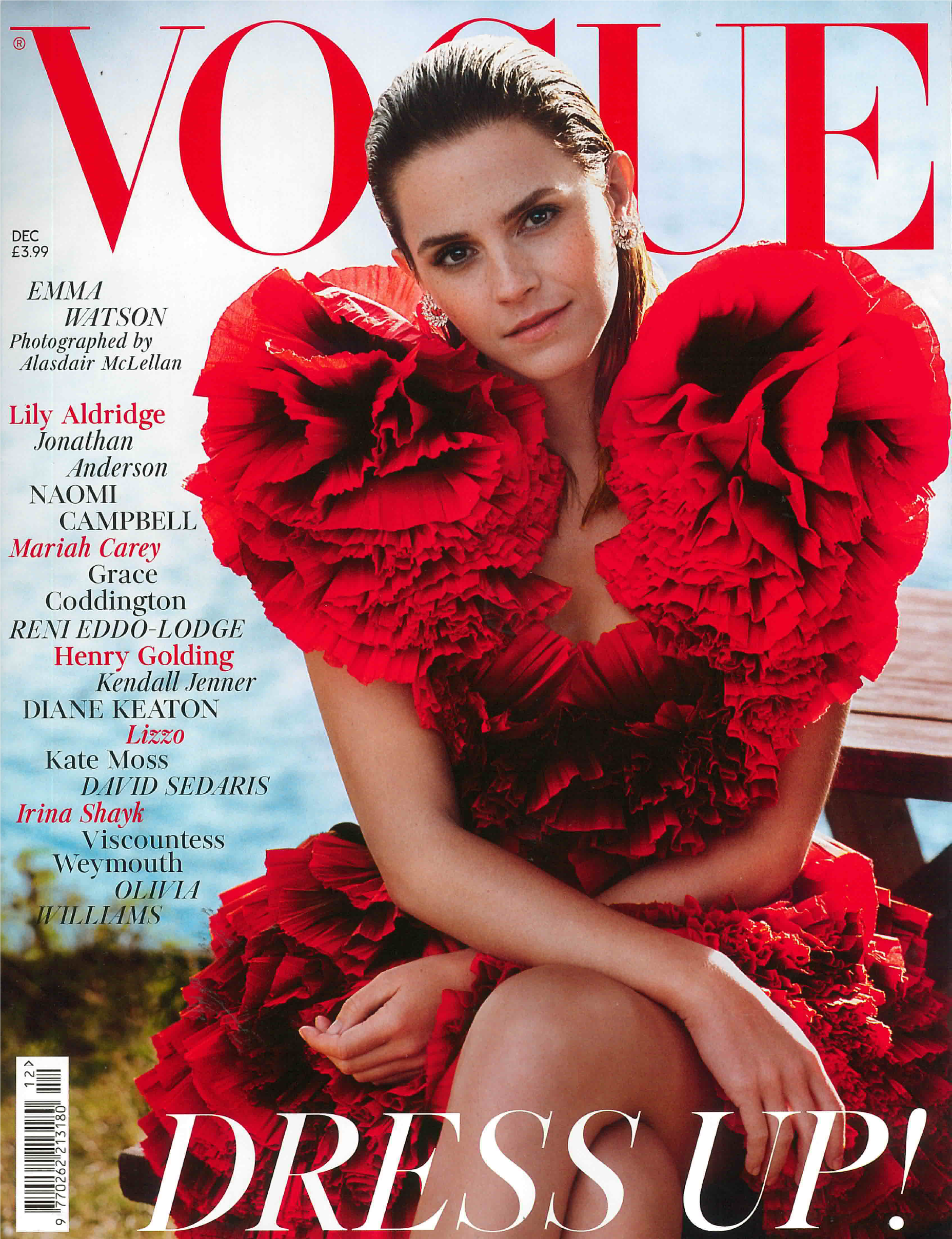Vogue magazine cover featuring actress Emma Watson wearing a dramatic red ruffled dress with large puffed sleeves, sitting outdoors with a blurred background of sky and trees.