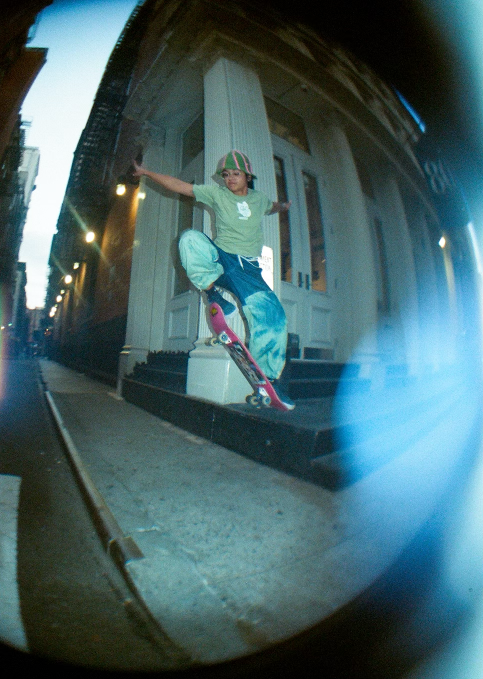 A person skateboarding on a small ledge outside a building in an urban area.