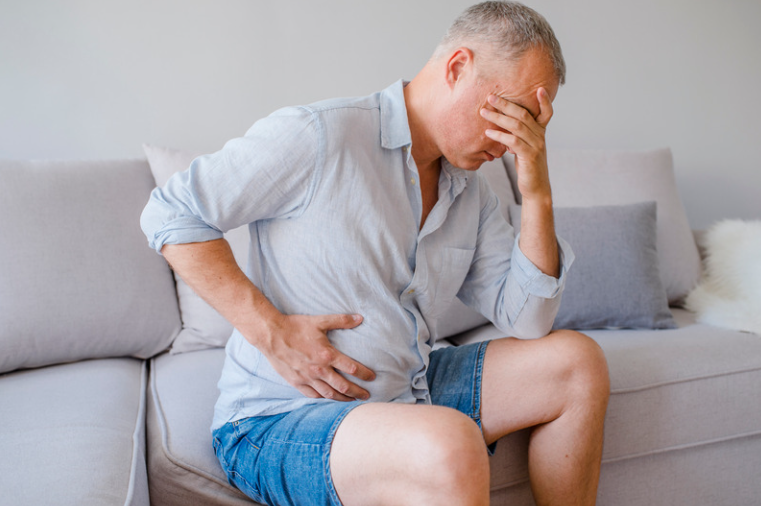male clutching stomach with pelvic health problem for example post prostatectomy