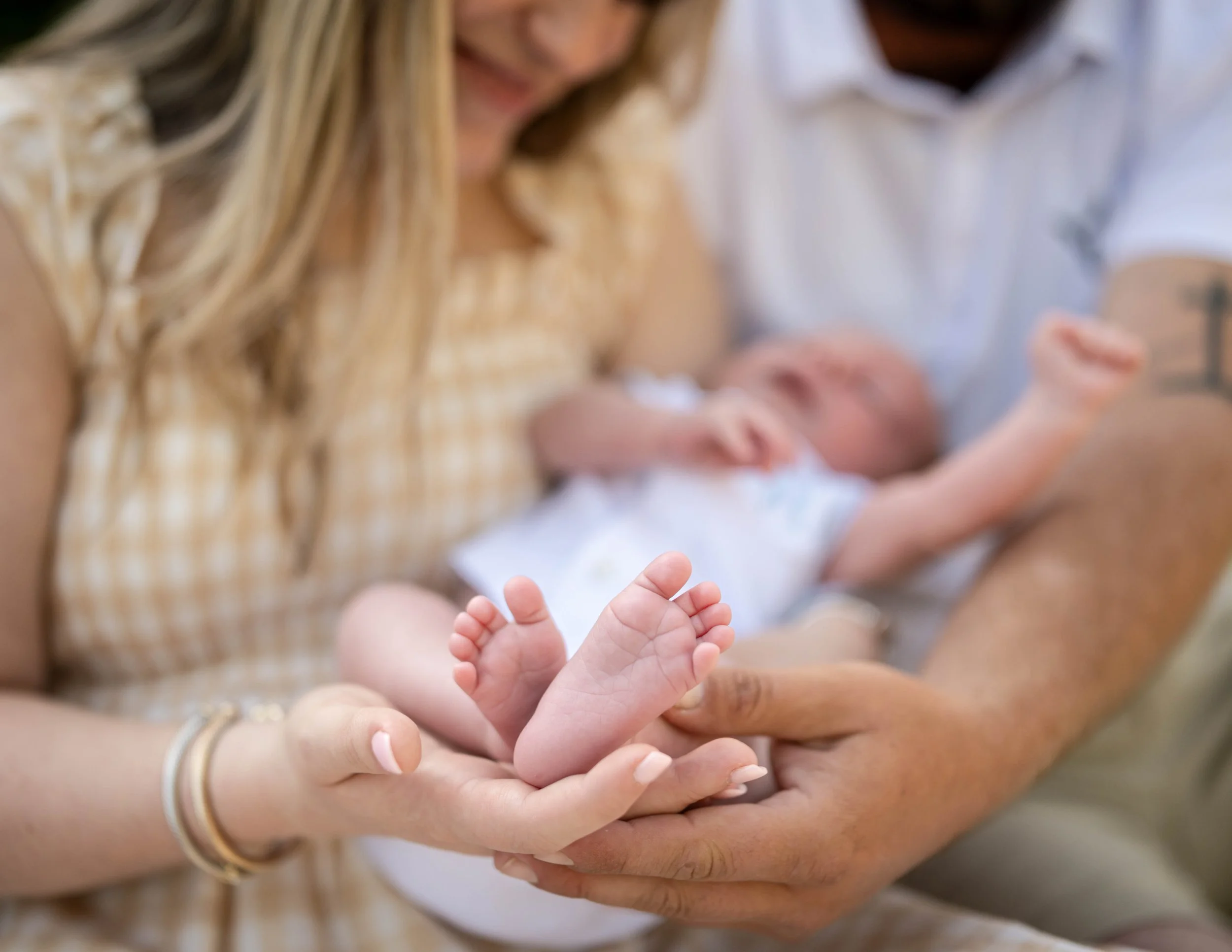Close-up of a woman holding a baby's hand, with both hands showing, blurred background.