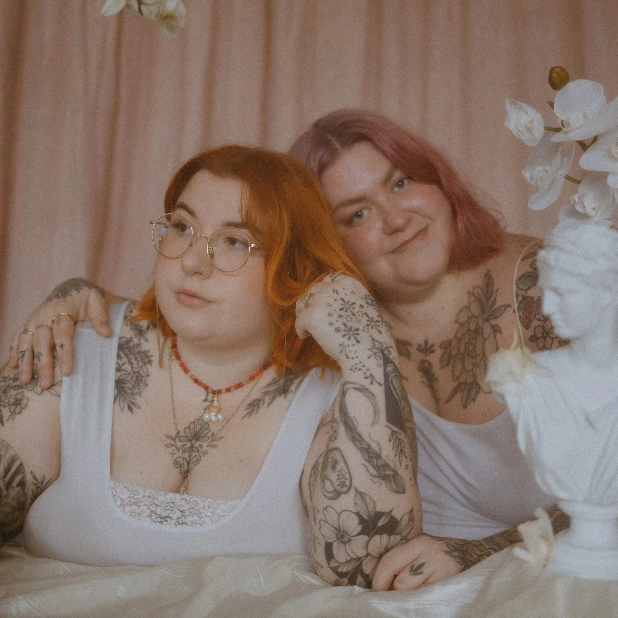 Alyssa and Holly Underwood pose together. Alyssa has orange hair and glasses while Holly has pink hair.