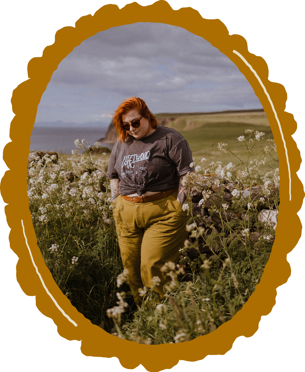 Alyssa stands in a field of wildflowers in Scotland wearing a Fleetwood Mac tshirt and olive green pants.