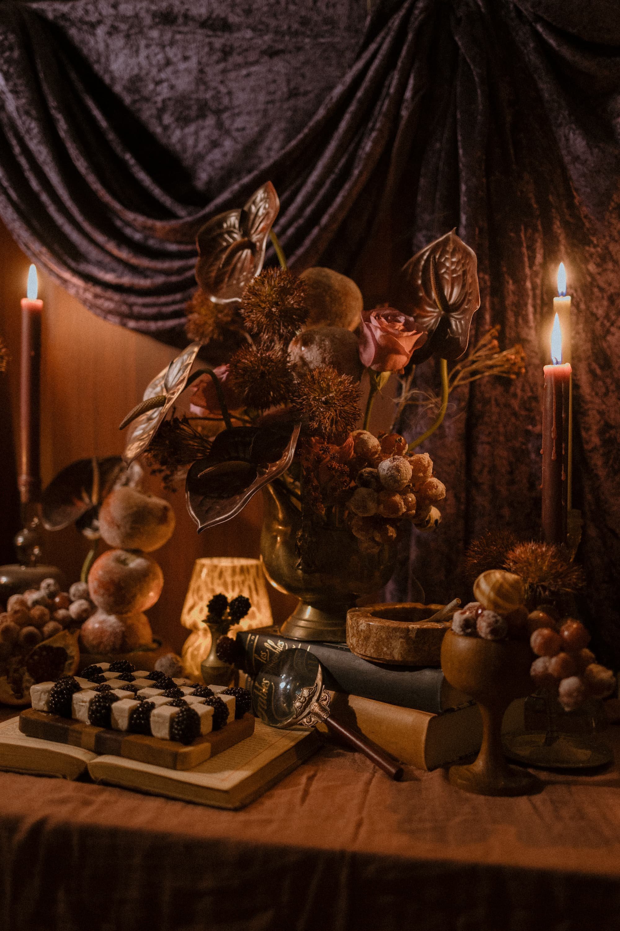 Sugared fruit, candles, books, and other home library accessories arranged by Love, The Underwoods. Featured in the center of the table is a small grazing board of feta and blackberries.