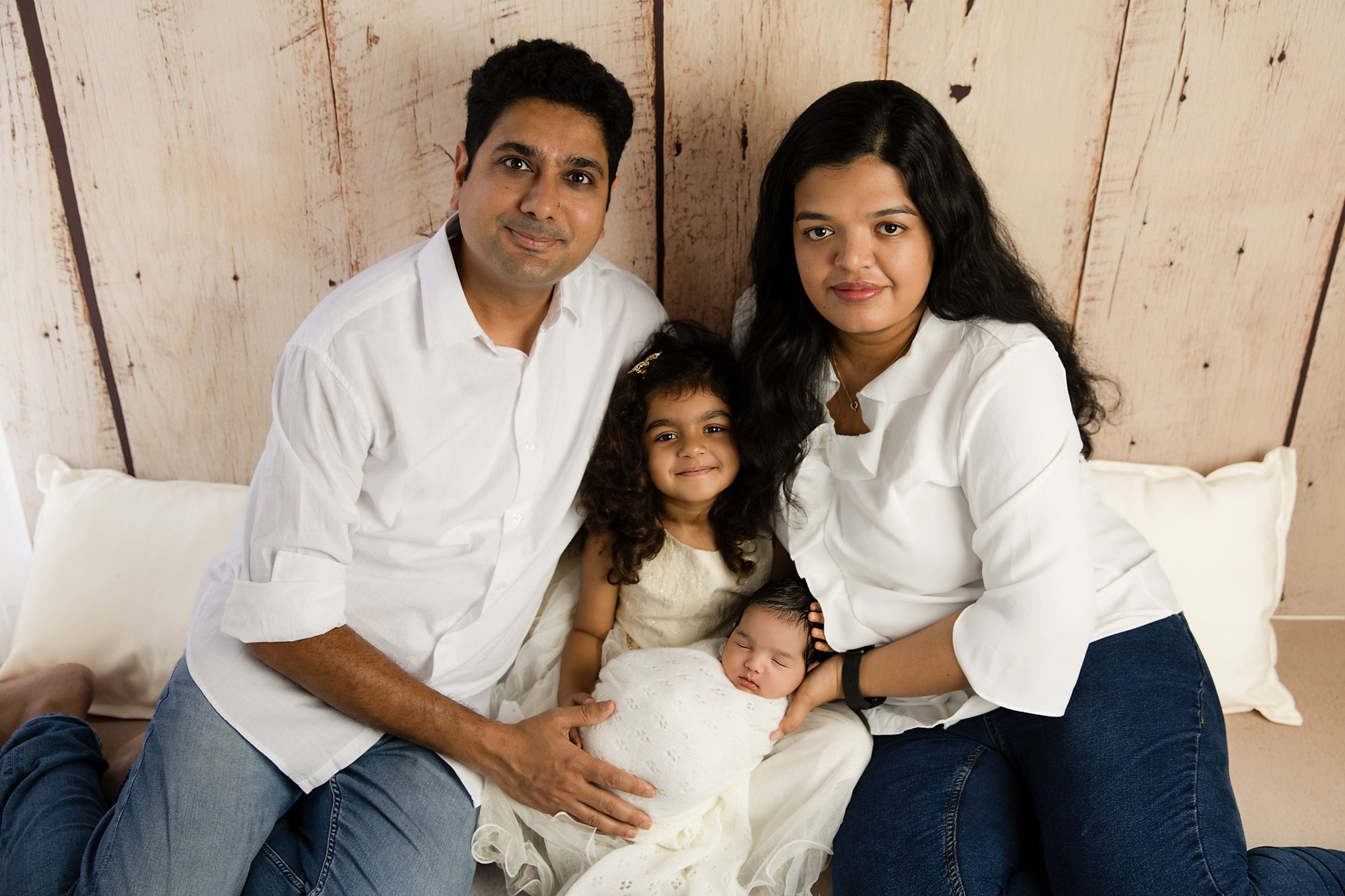 family-of-four-with-a-newborn-baby-girl-posing-against-a-wooden-background-dressed-in-denim-jeans-and-white-tops_1C3A3862-copy.jpg