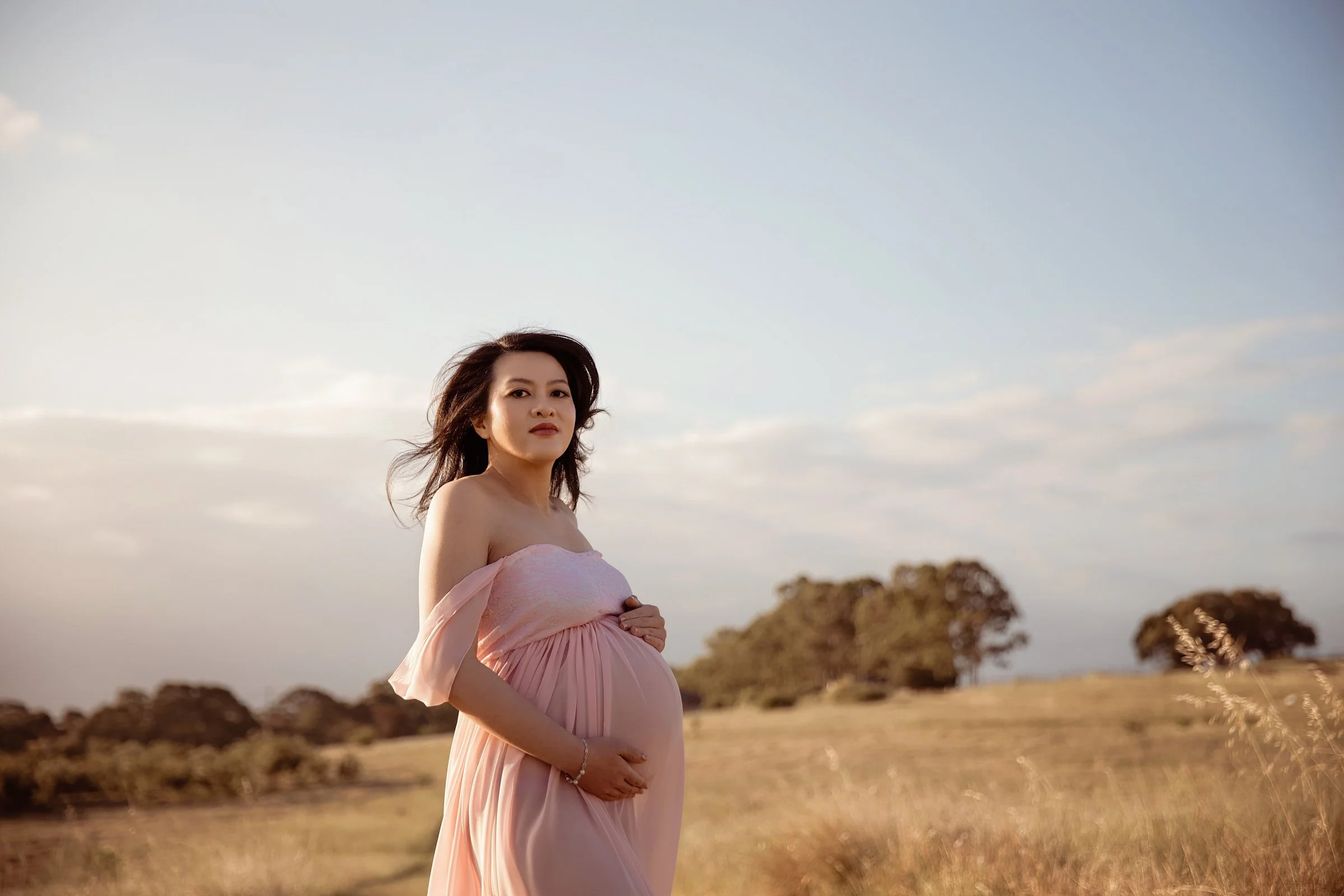 Powerful maternity portrait of a mum-to-be in a grassy field of Sydney during her mini maternity session