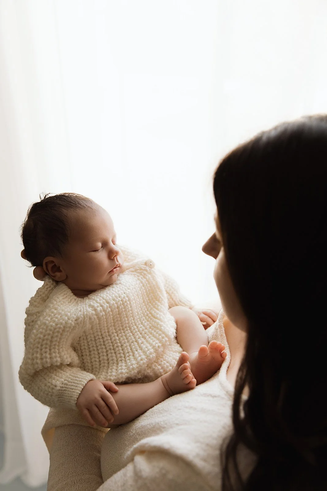 backlit-image-of-a-newborn-in-mums-hands-wearing-knitted-cream-romper_relaxed-newborn-studio-session1C3A9051-copy.jpg