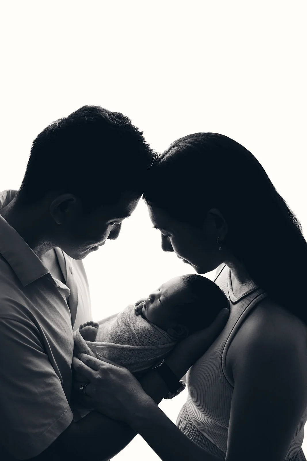 First-time parents cradling their newborn baby in a backlit window setting, Hills District family photography