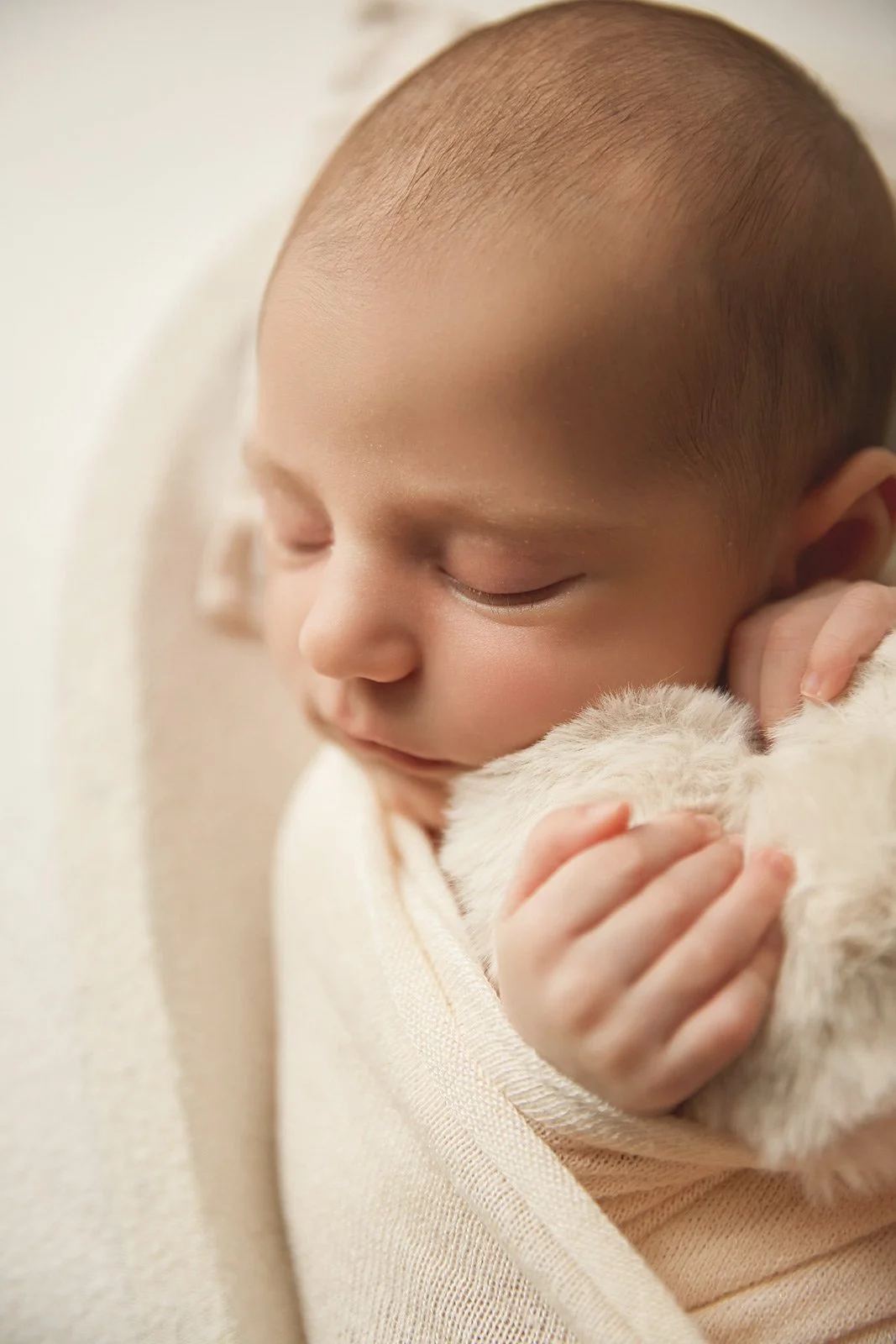 Close-up of a sleeping young child with a puppy, with the child gently hugging the puppy.