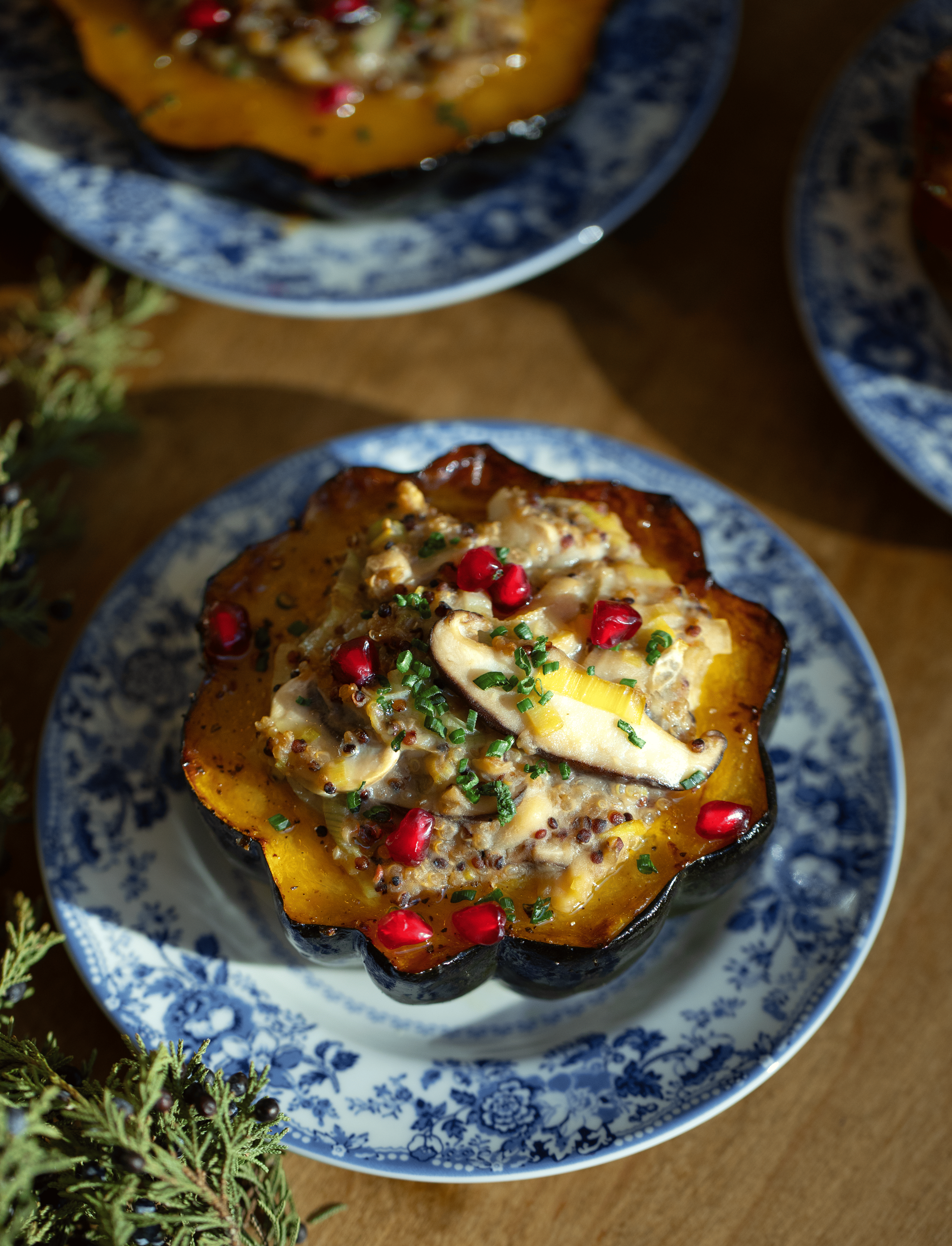 Baked stuffed pumpkin with cheese, herbs, and pomegranate seeds on a blue and white floral plate.
